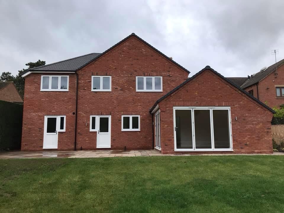 Finished four-bedroom red brick detached new-build house on High Street, Inkberrow, Worcestershire, with grey plain tile roof, aluminium bifold doors and landscaped rear garden — built by JRC Developers (J. Coote & Son Ltd)