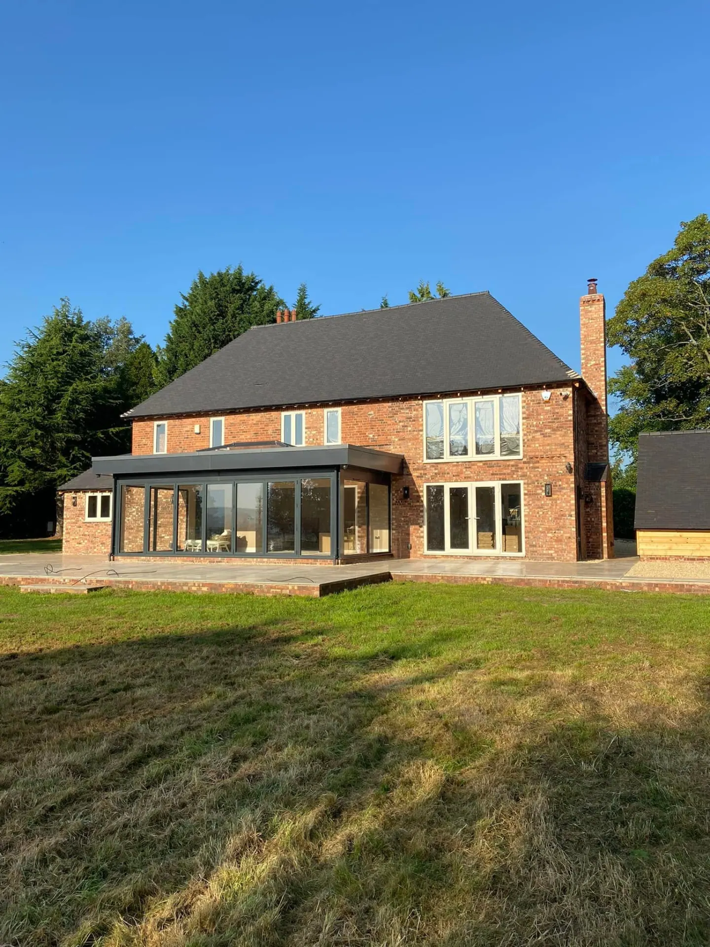 Full rear elevation of the completed remodelled house with the new garden room and expansive terrace