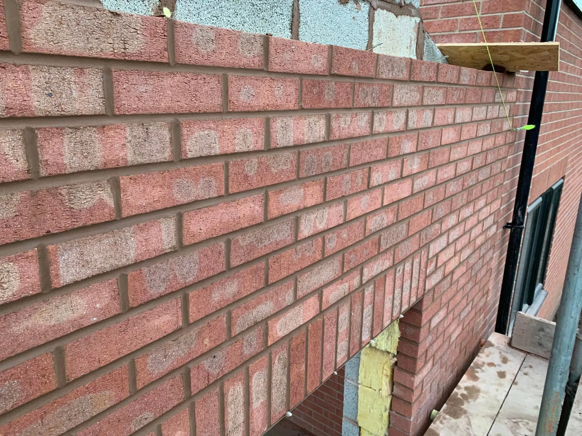 Cavity wall brickwork with insulation and wall ties visible at the head of the wall on the side extension