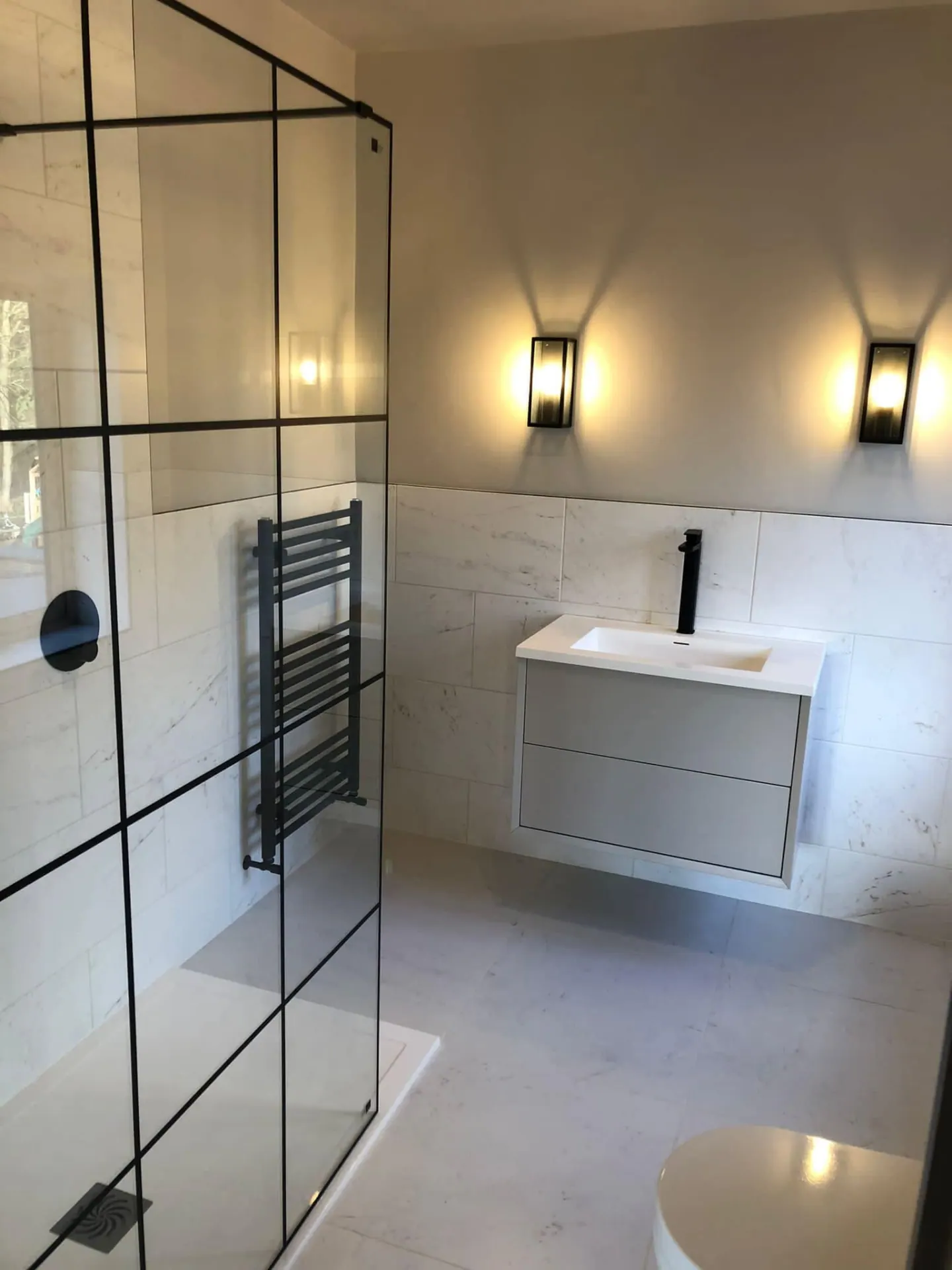 Finished shower room with black shower screen, floating vanity and modern wall lights
