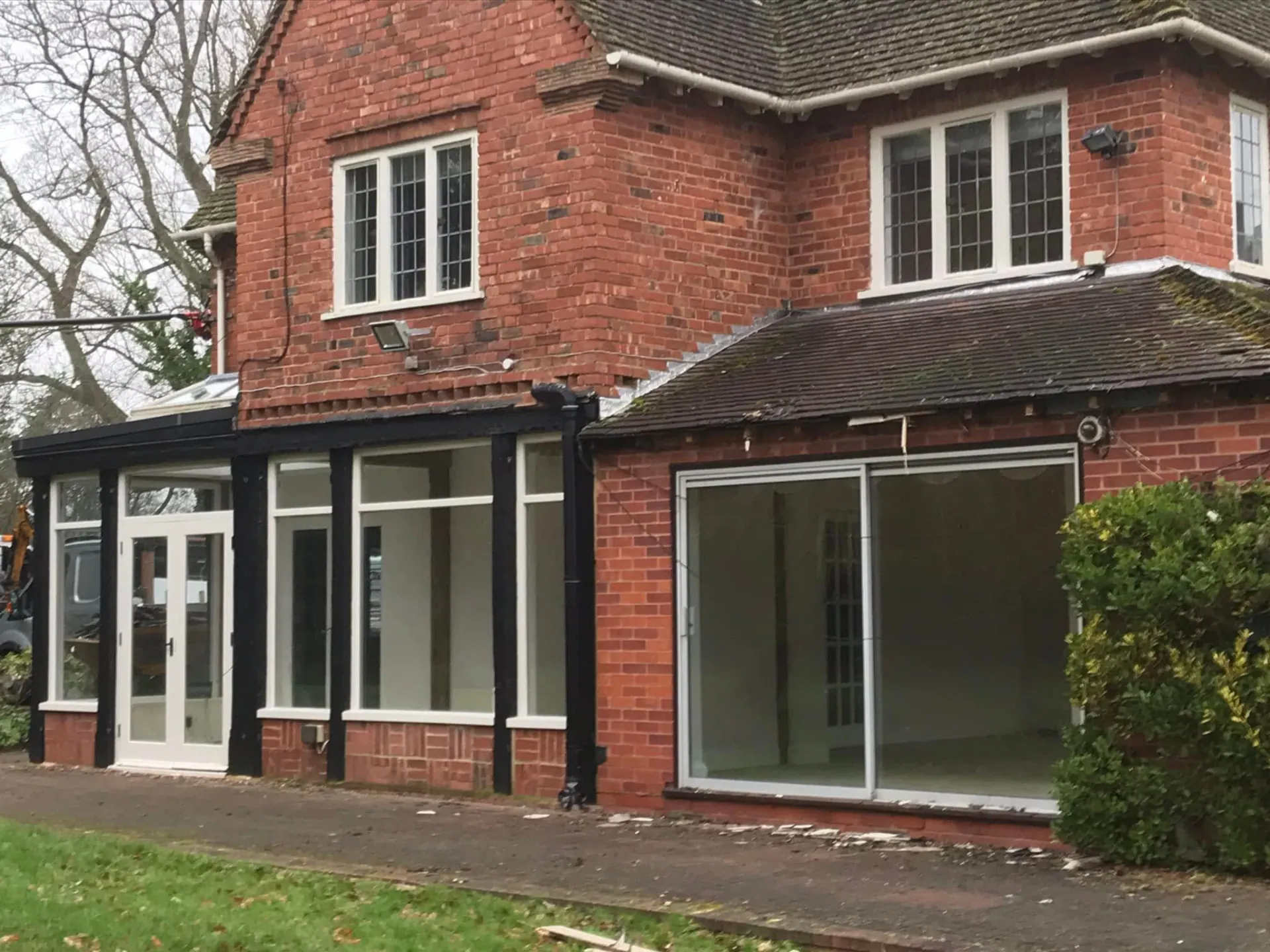 Rear elevation of the property before the full remodelling, showing an older conservatory-style rear addition and dated openings