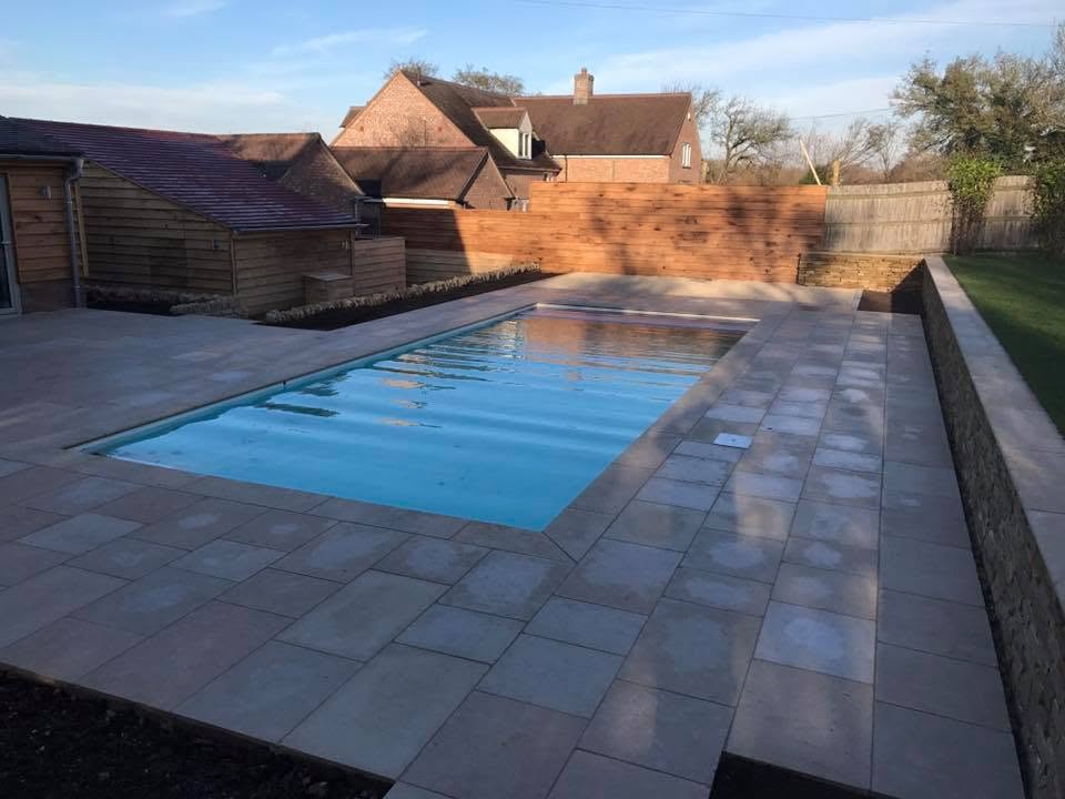 Limestone paved pool terrace linking the swimming pool, oak-clad outbuilding and oak privacy screen