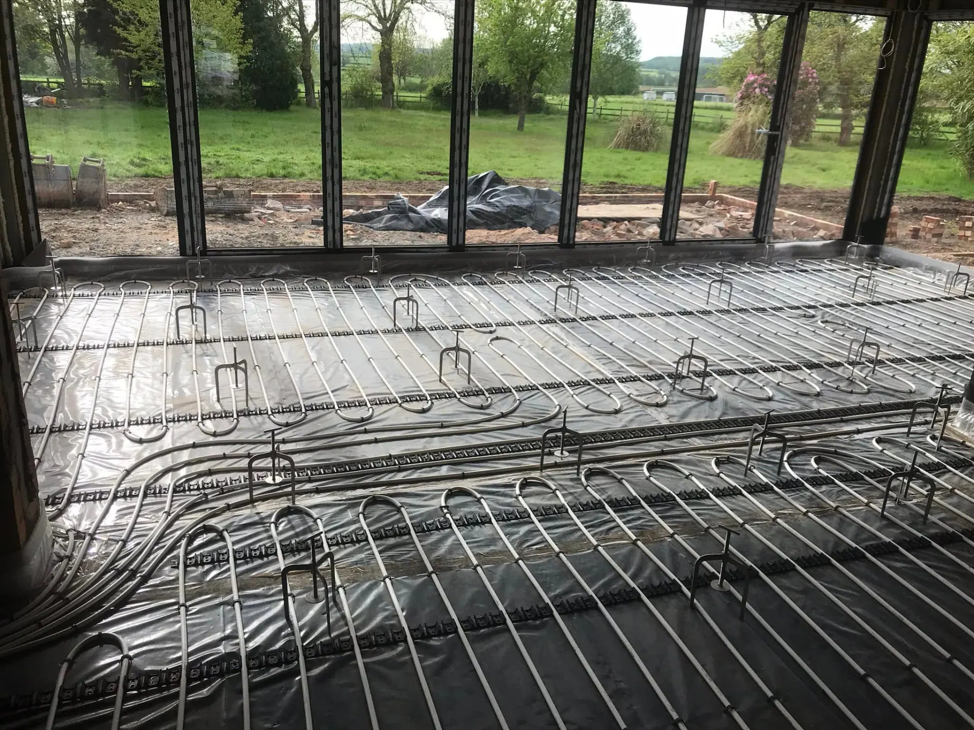 Underfloor heating pipework laid across the new rear extension floor before screed in the glazed garden room area