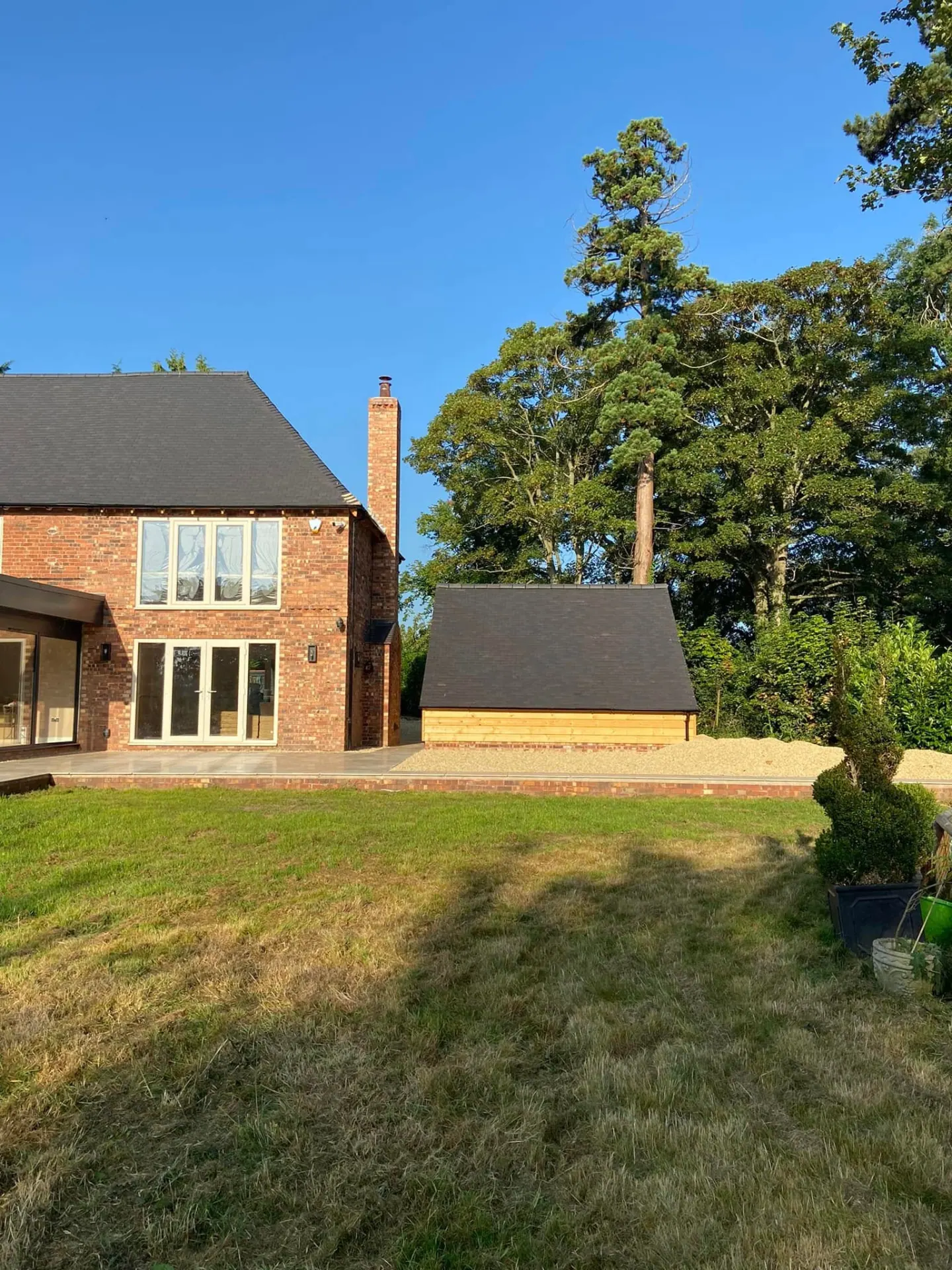 View of the completed rear corner of the remodelled house with the oak-clad outbuilding beyond