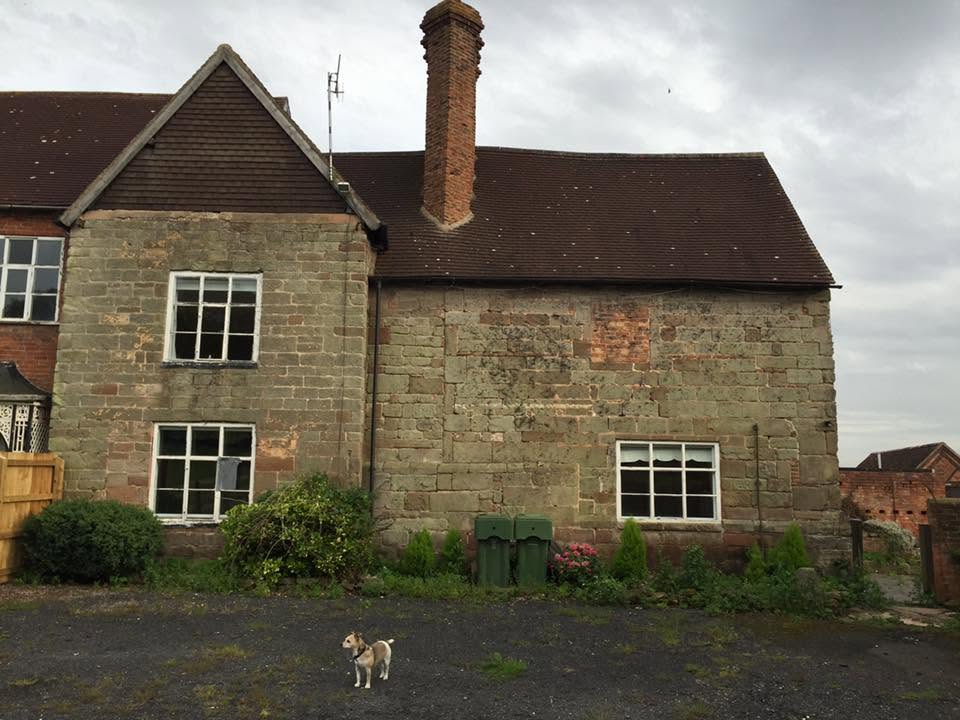Before restoration — close view of the listed farmhouse gable showing open-jointed sandstone, historic brick infill patching and failing window frames