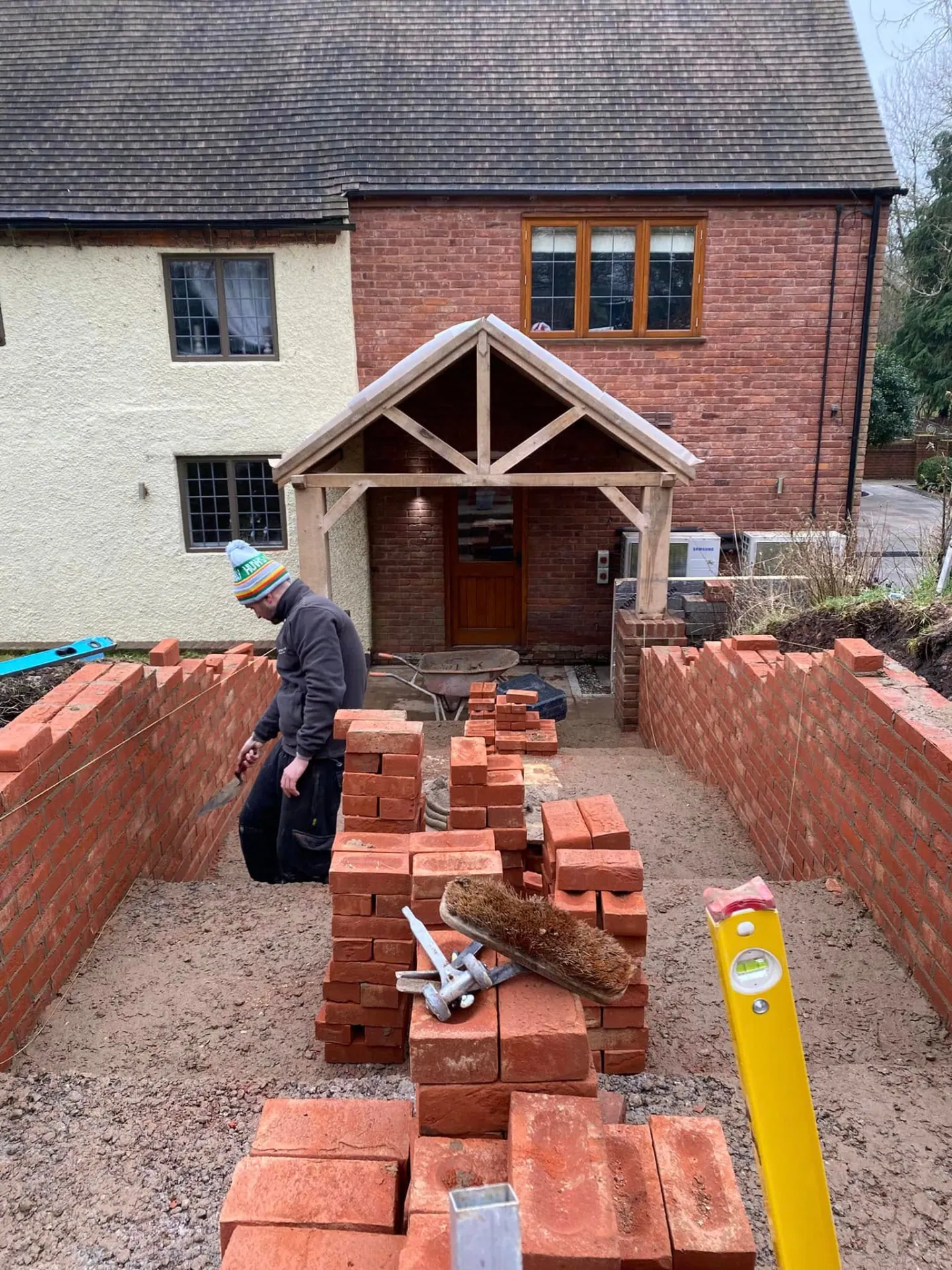 Oak porch frame complete with the brick retaining walls to the new path under construction in front of it