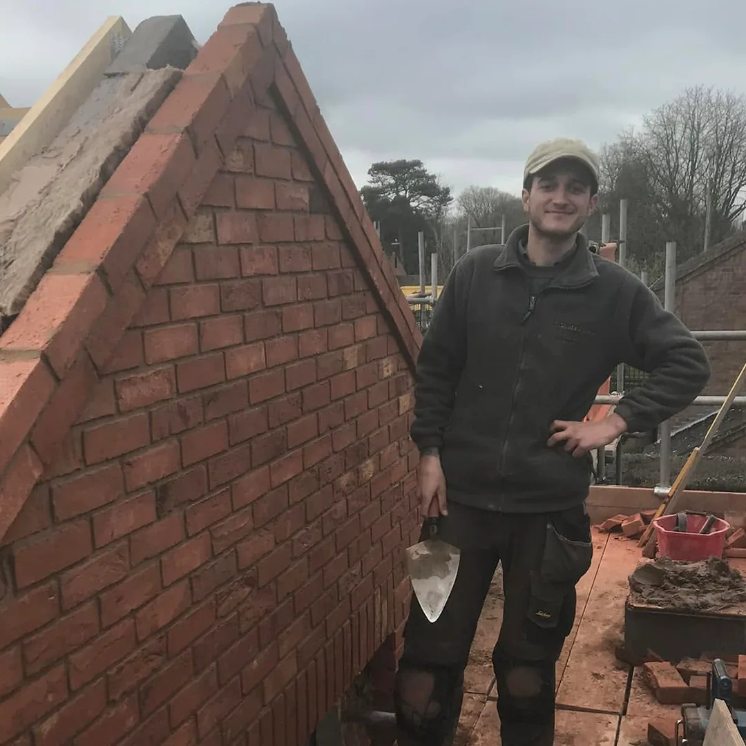 Jack with his trowel beside a newly built red brick gable