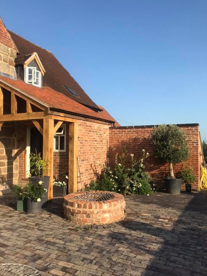Finished courtyard at the Grade II listed farmhouse with the restored brick well, oak-framed porch, clay tiled roof and repaired brick boundary wall