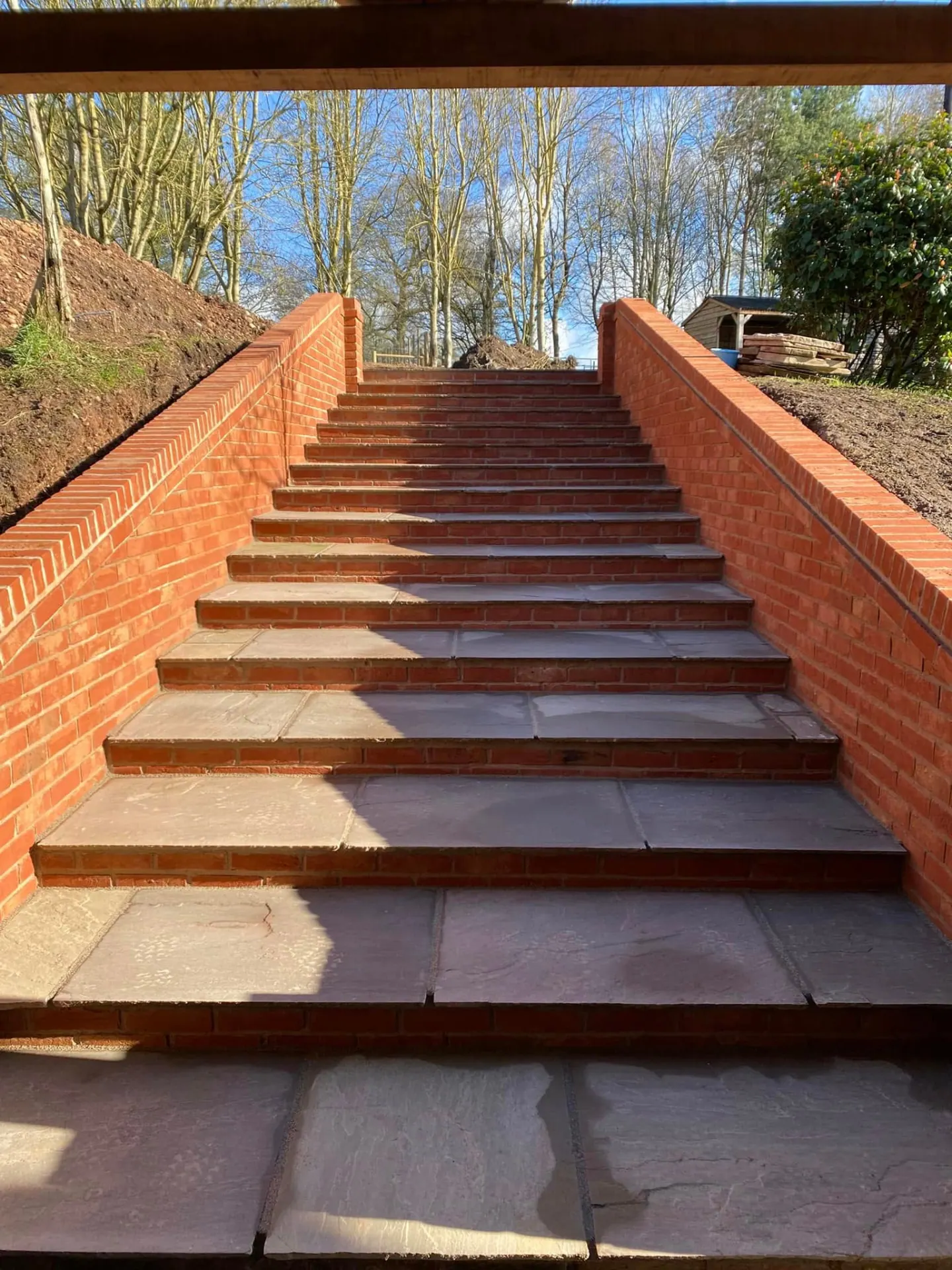 The new brick and sandstone garden steps viewed from the bottom, framed by the oak porch beams