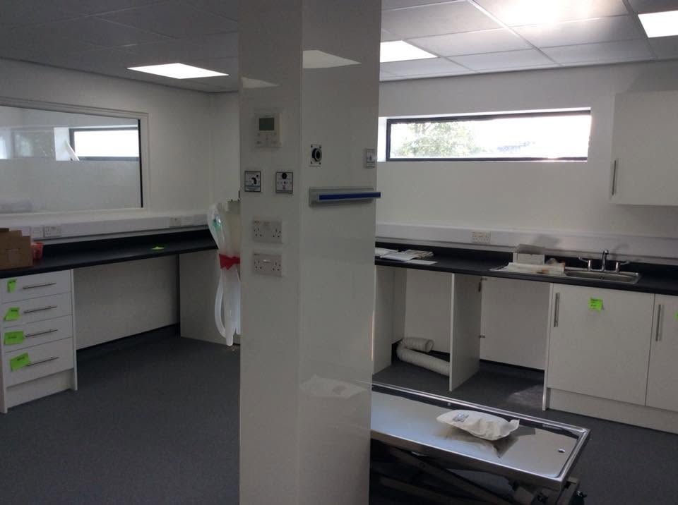 Veterinary prep area with laboratory worktops, stainless sink, under-counter units, high-level windows and a stainless treatment table