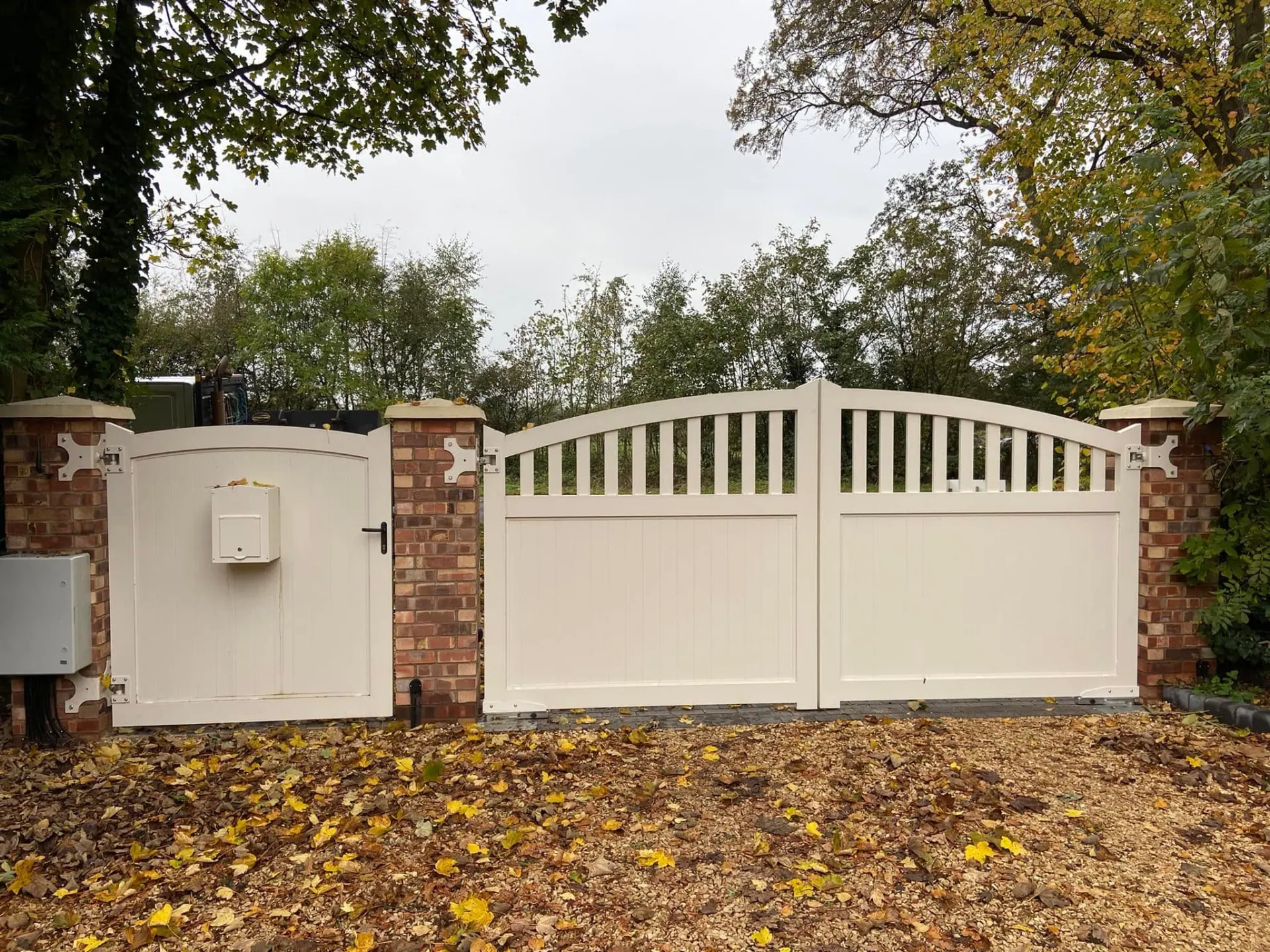 White entrance gates and matching pedestrian gate between brick piers at Wootton Mead