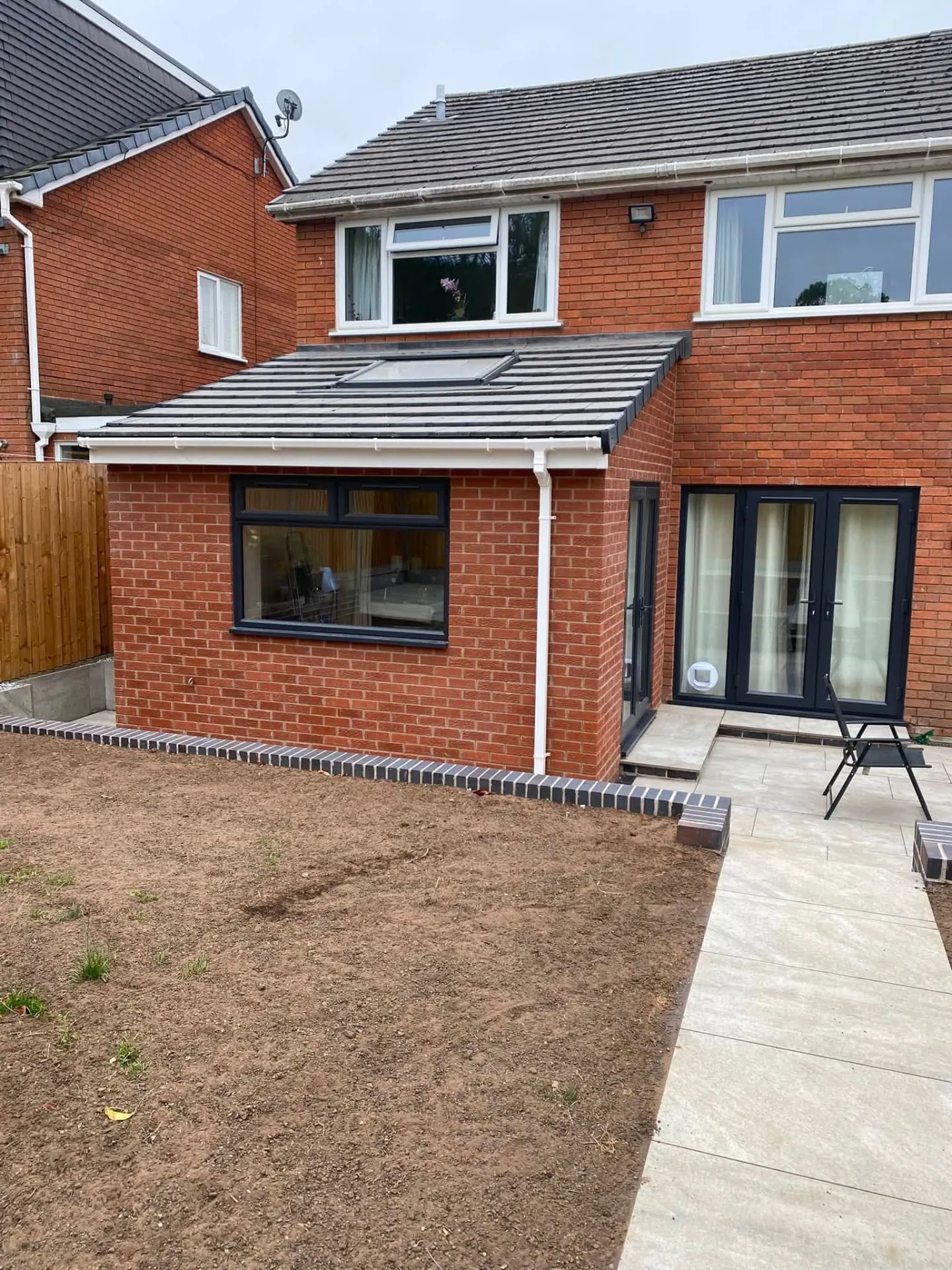 Completed rear lounge extension in Worcestershire by JRC Developers — red brick single-storey extension with grey tiled roof, rooflight, anthracite window and porcelain patio