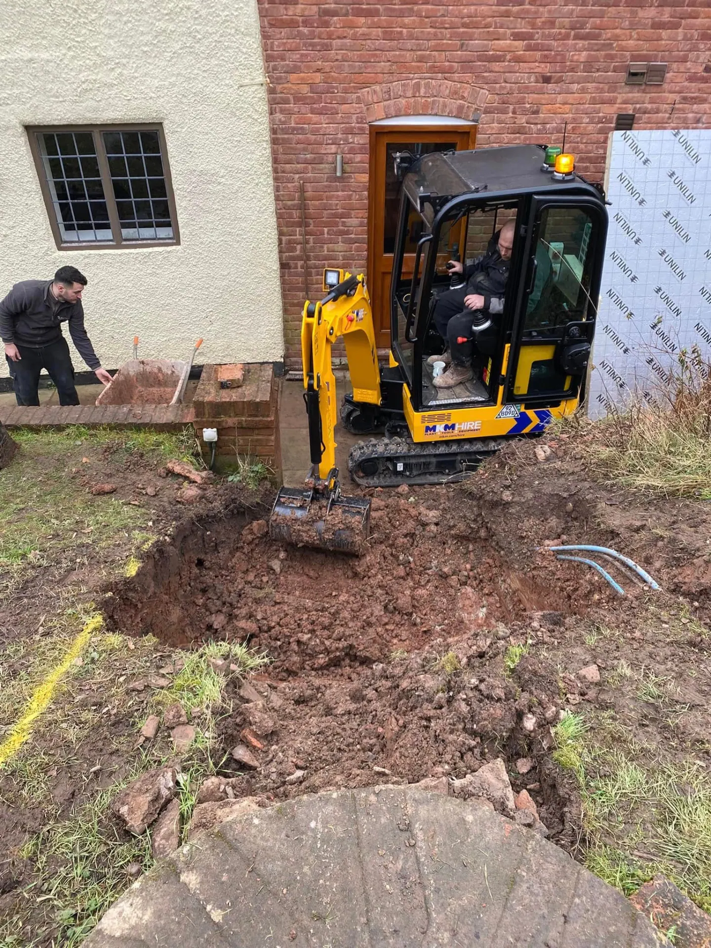 Mini excavator digging out foundations for the new oak porch and retaining walls, with buried services exposed