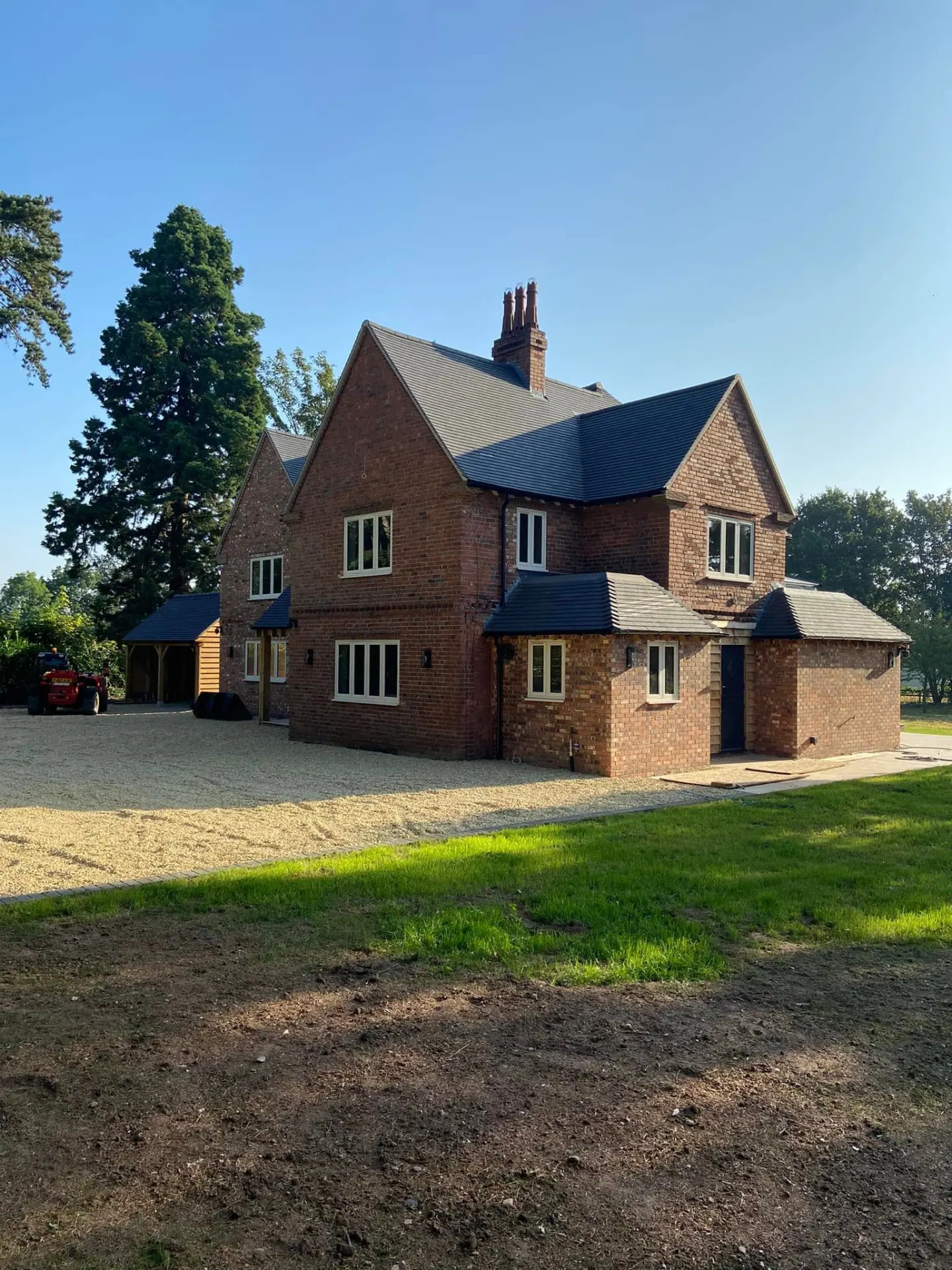 Completed front and side view of Wootton Mead showing the remodelled house, gravel drive and oak-clad outbuilding