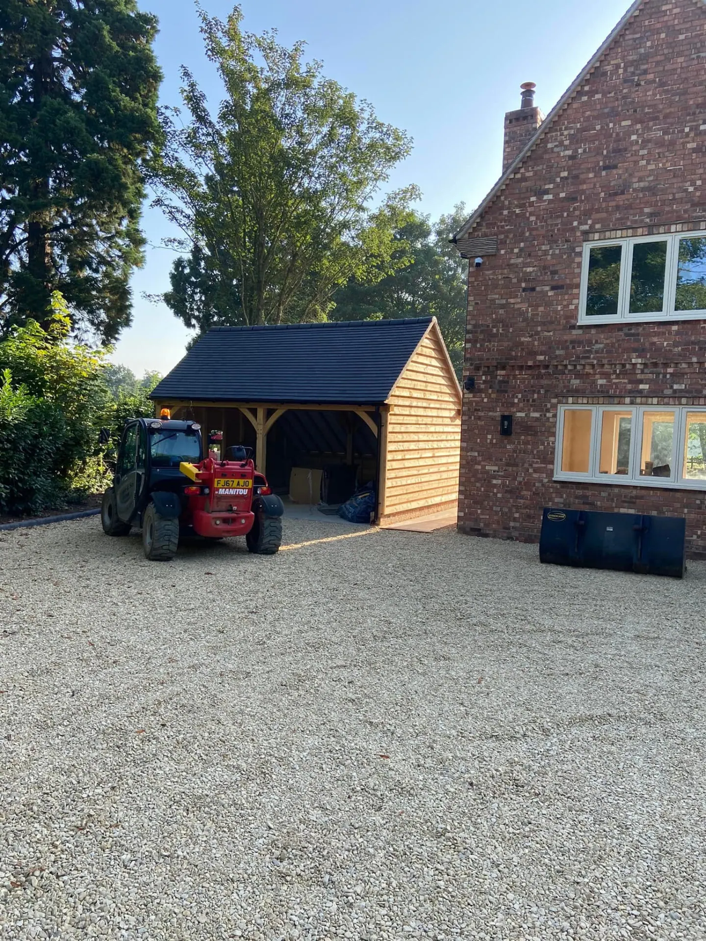 Oak-clad outbuilding finished beside the gravel drive at Wootton Mead with telehandler in the foreground