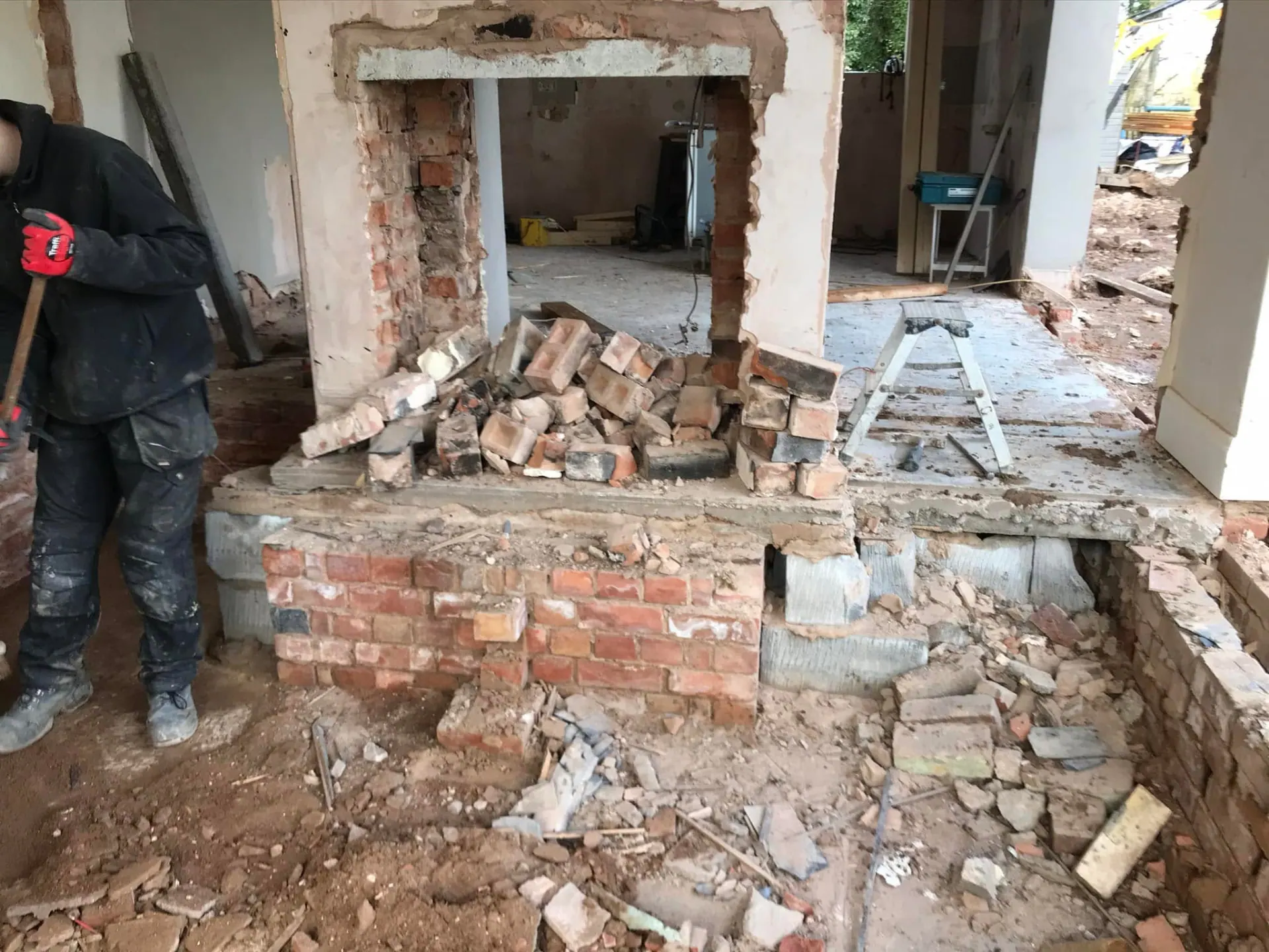 Interior demolition in progress with broken-out masonry and floor levels exposed during the house remodelling
