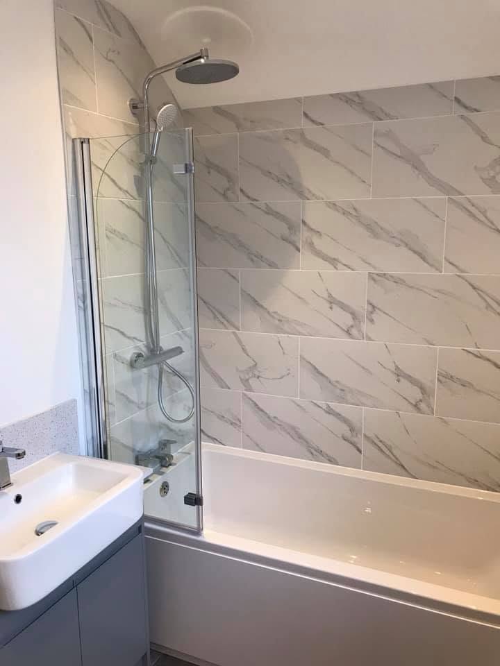 Family bathroom with marble-effect tiling and rain shower at the Inkberrow new-build
