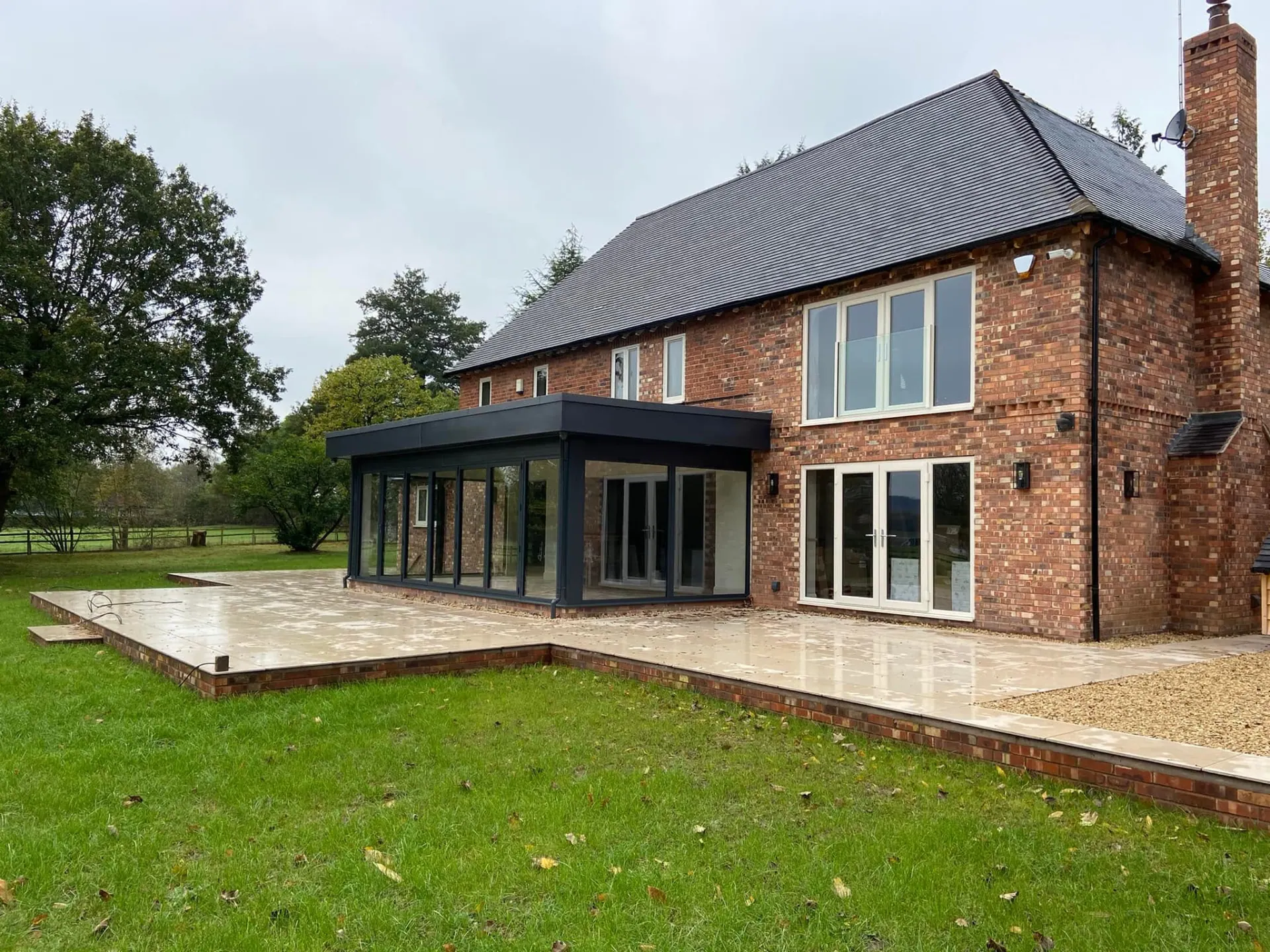 Completed rear terrace and glazed garden room on the remodelled house viewed from the lawn