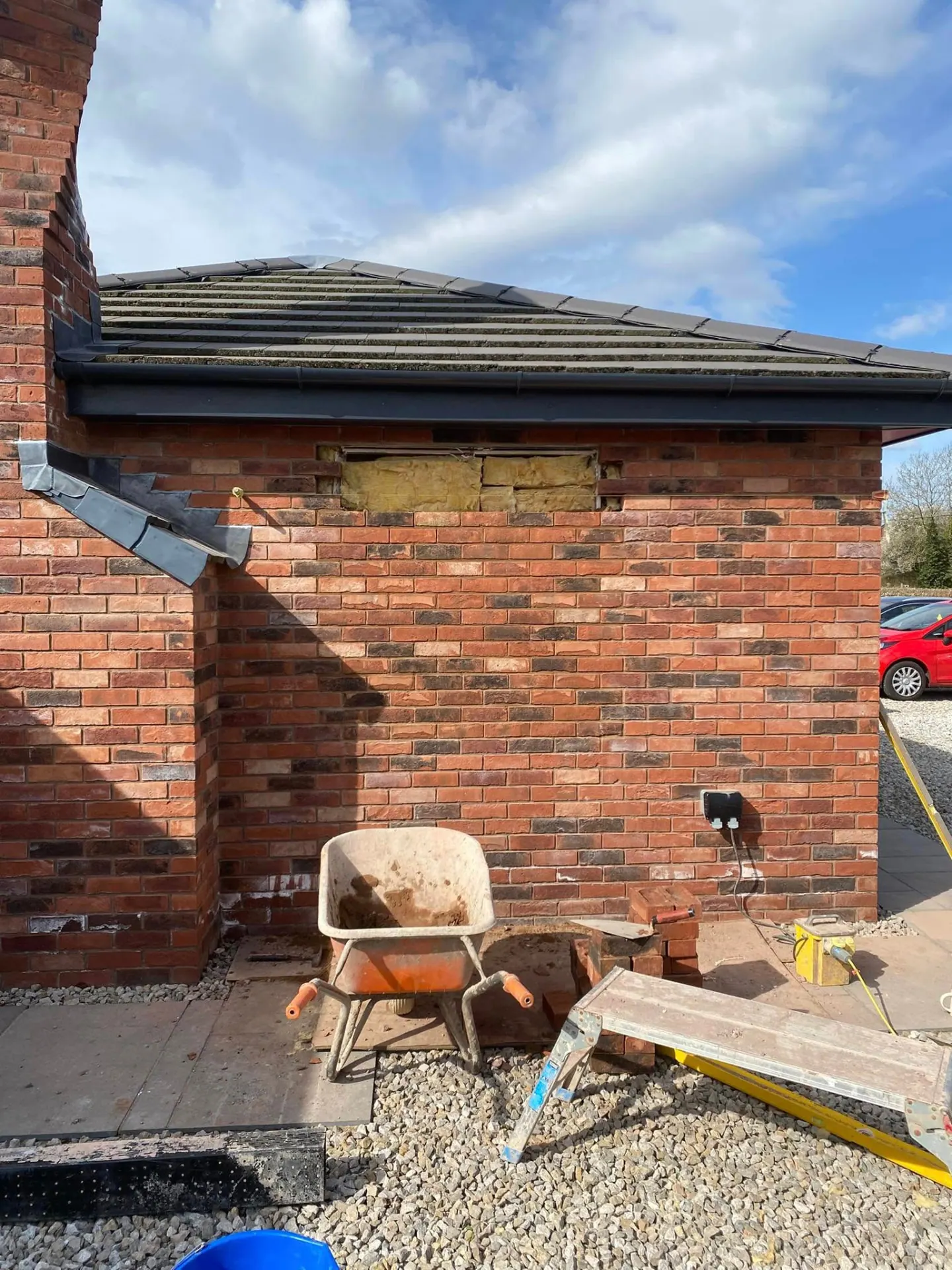 New window opening cut into a brick elevation showing exposed cavity insulation before the lintel and reveals are built