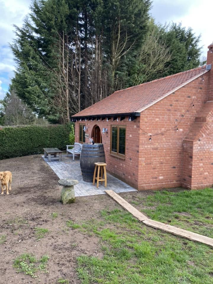 Finished detached red brick man cave and garden bar with clay tiled roof, arched oak door and block paved terrace in Worcestershire