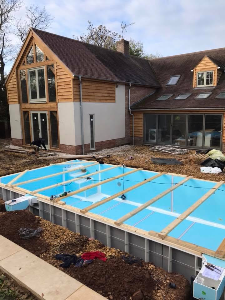 Steel panel swimming pool shell installed and braced with timber, with the oak-framed extension behind