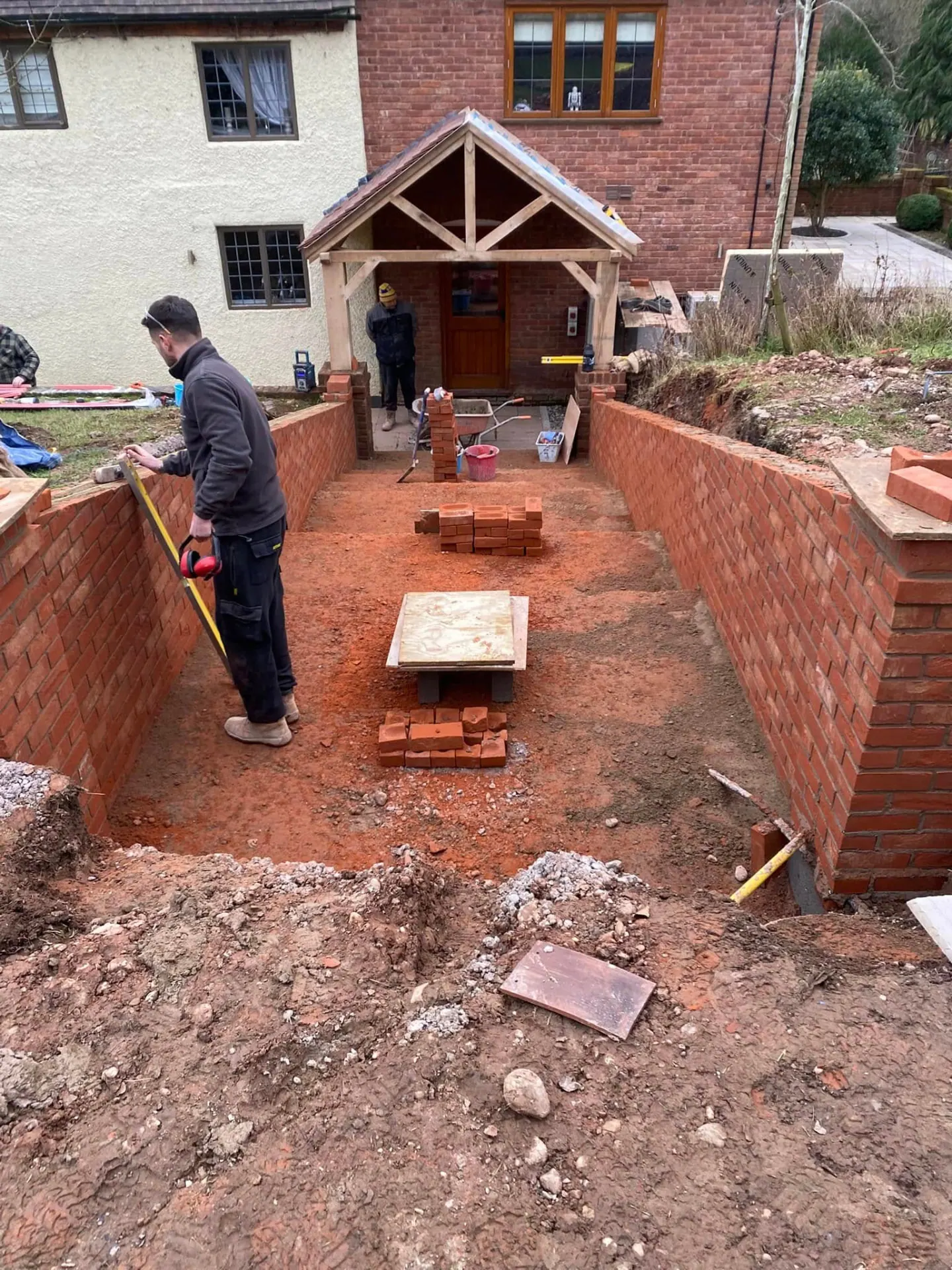 JRC Developers bricklayer measuring the new brick retaining walls forming the sandstone path towards the oak porch