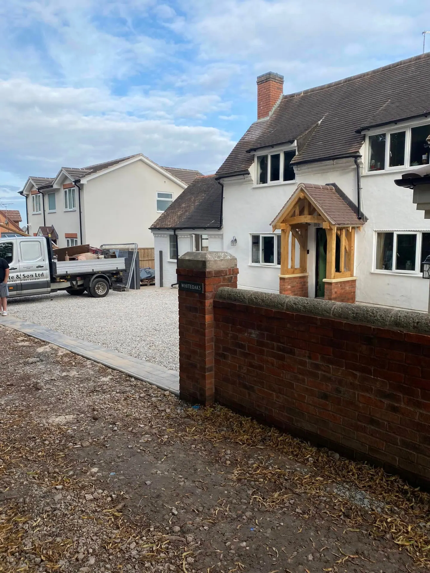 Whiteoaks in Worcestershire after completion — white rendered cottage with a hand-cut oak porch, new gravel driveway and reclaimed brick boundary wall built by JRC Developers