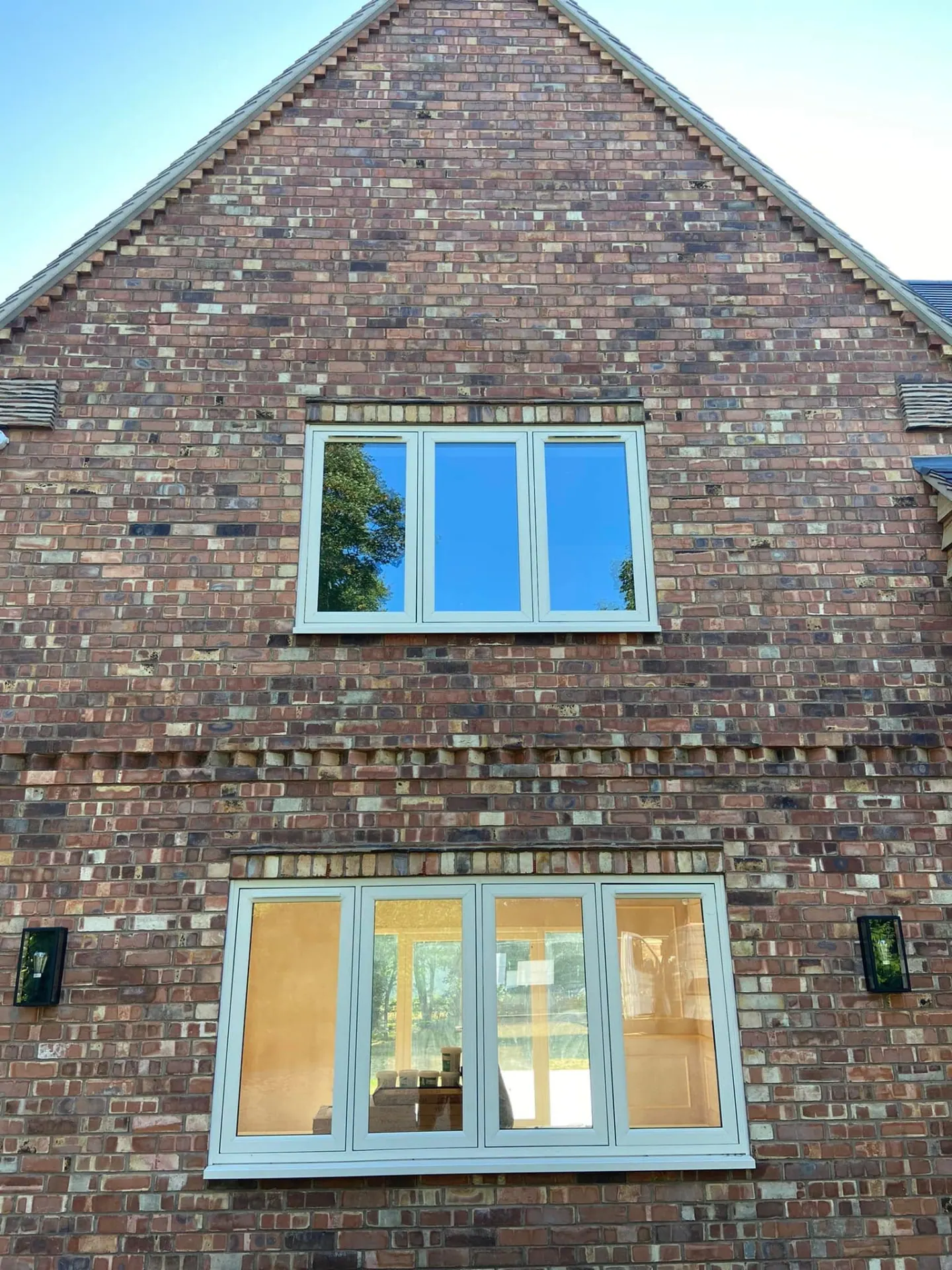 Finished brick gable elevation with cream-framed windows and dentil brick details at Wootton Mead