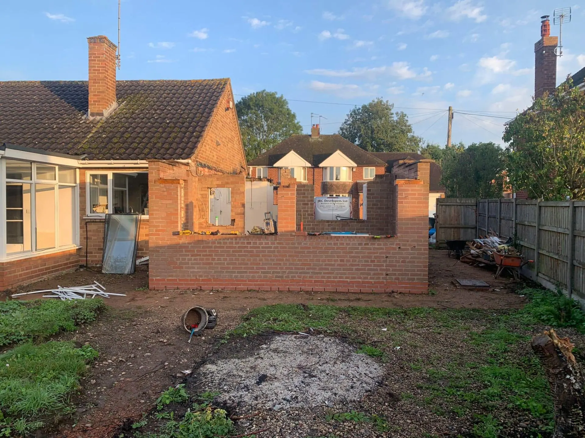 Mid-demolition rear view of White Gates with new red brickwork rising off fresh footings and the JRC Developers site signboard on the wall