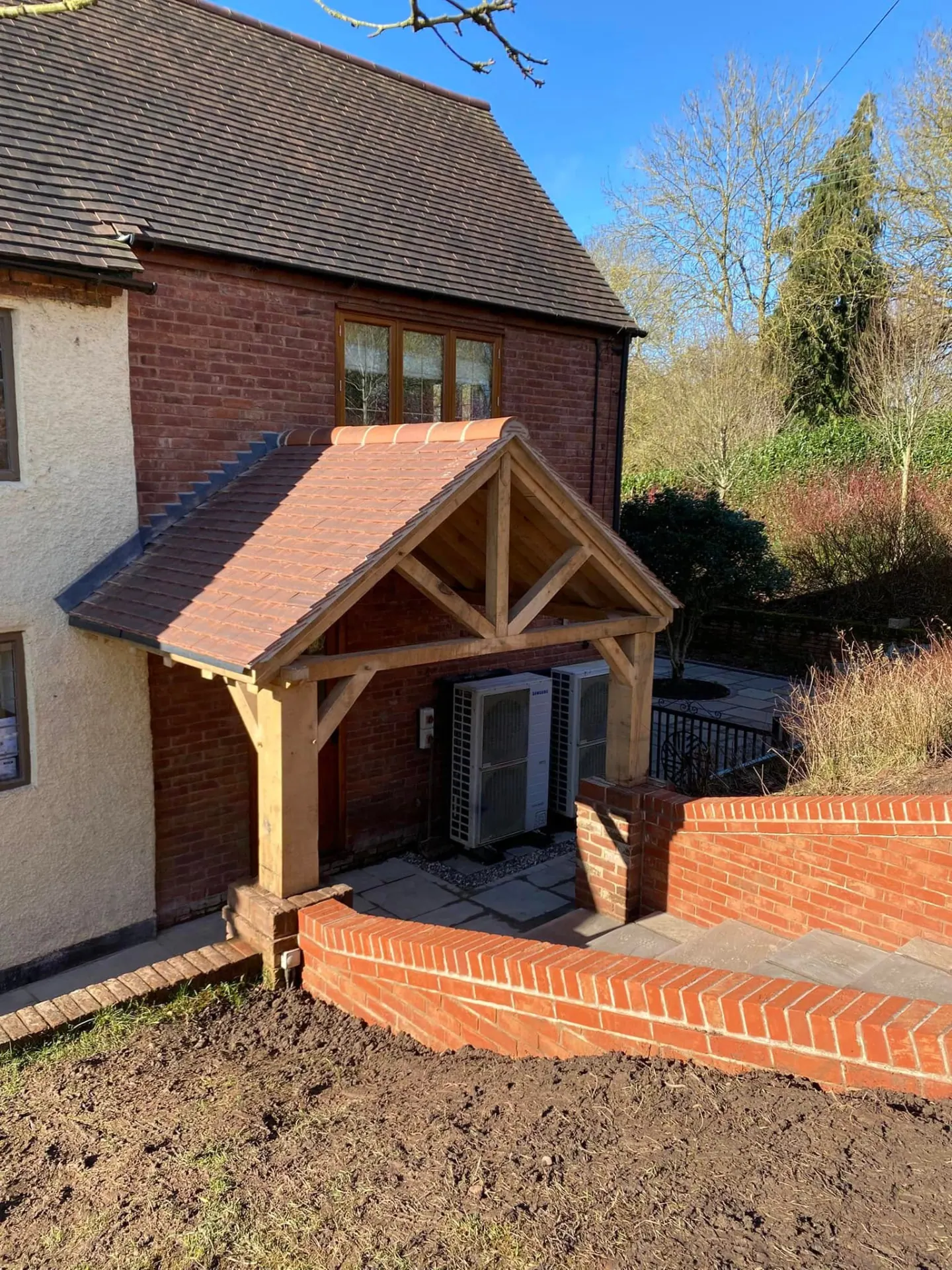 Finished hand-cut oak-framed porch with clay tiled roof and new red brick retaining walls at a Worcestershire country house, built by JRC Developers