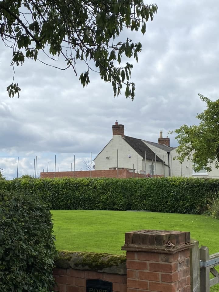 Two-storey red brick side extension under construction on a rendered period farmhouse in Worcestershire, with scaffolding and cut-roof timber trusses in place — built by JRC Developers
