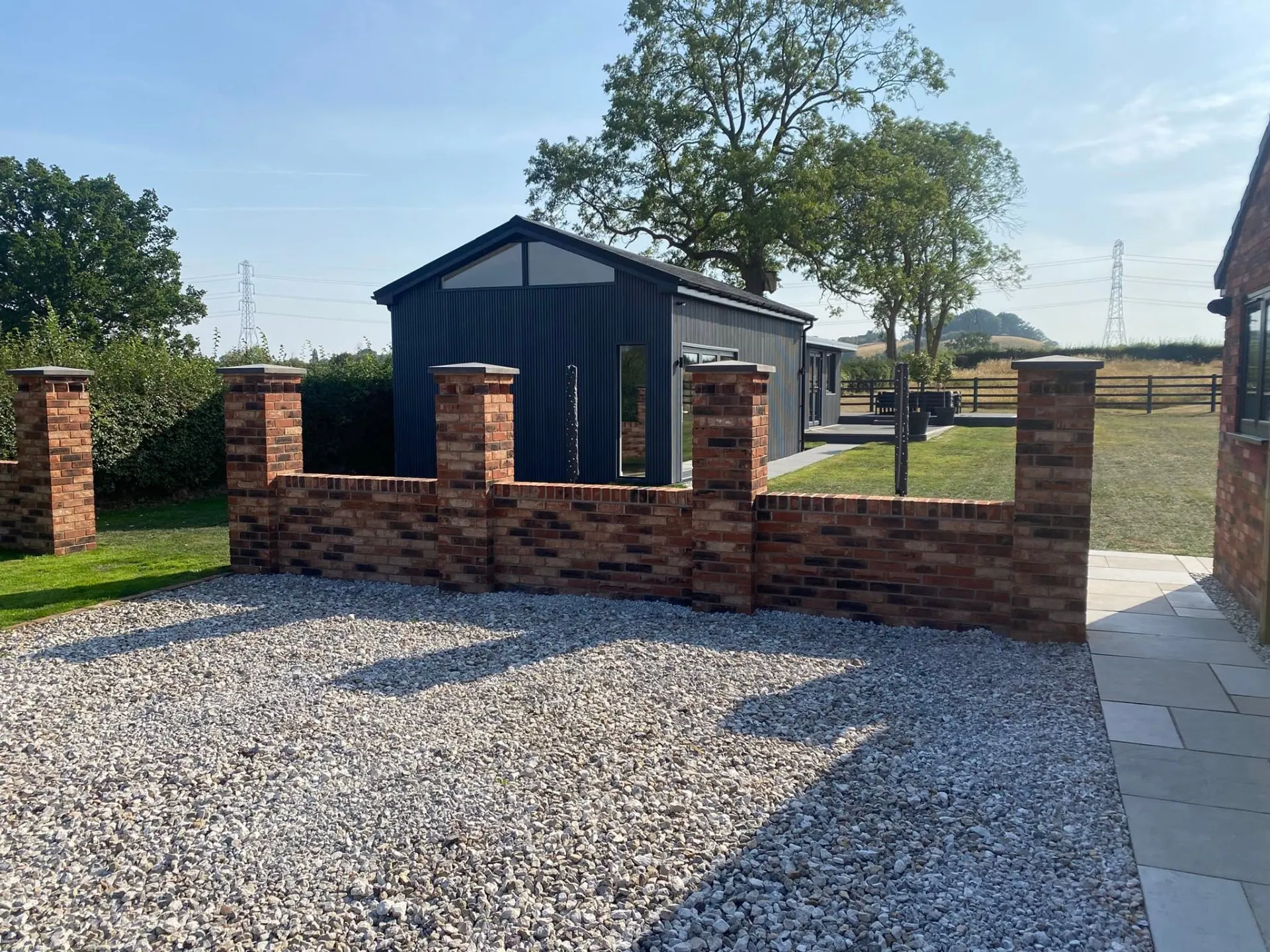 JRC-built new-build bungalow in Worcestershire with a dark clad golf swing room, glazed gable, new red brick walls and capped pillars on a gravel driveway