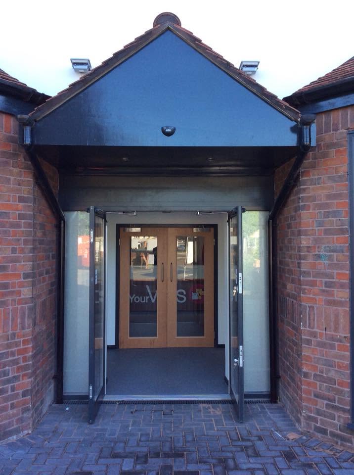 Covered entrance canopy of the veterinary practice with glazed screens, timber double doors and block paving approach