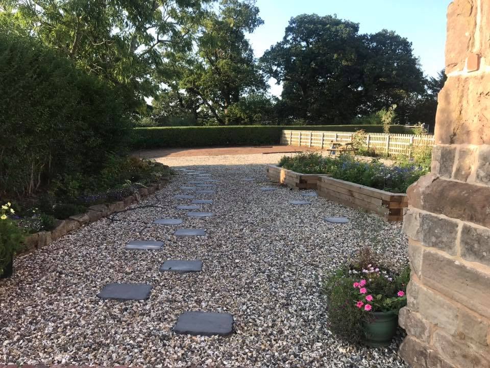 New gravel driveway with riven stone stepping stones and oak sleeper raised beds at the restored Grade II listed farmhouse in Worcestershire