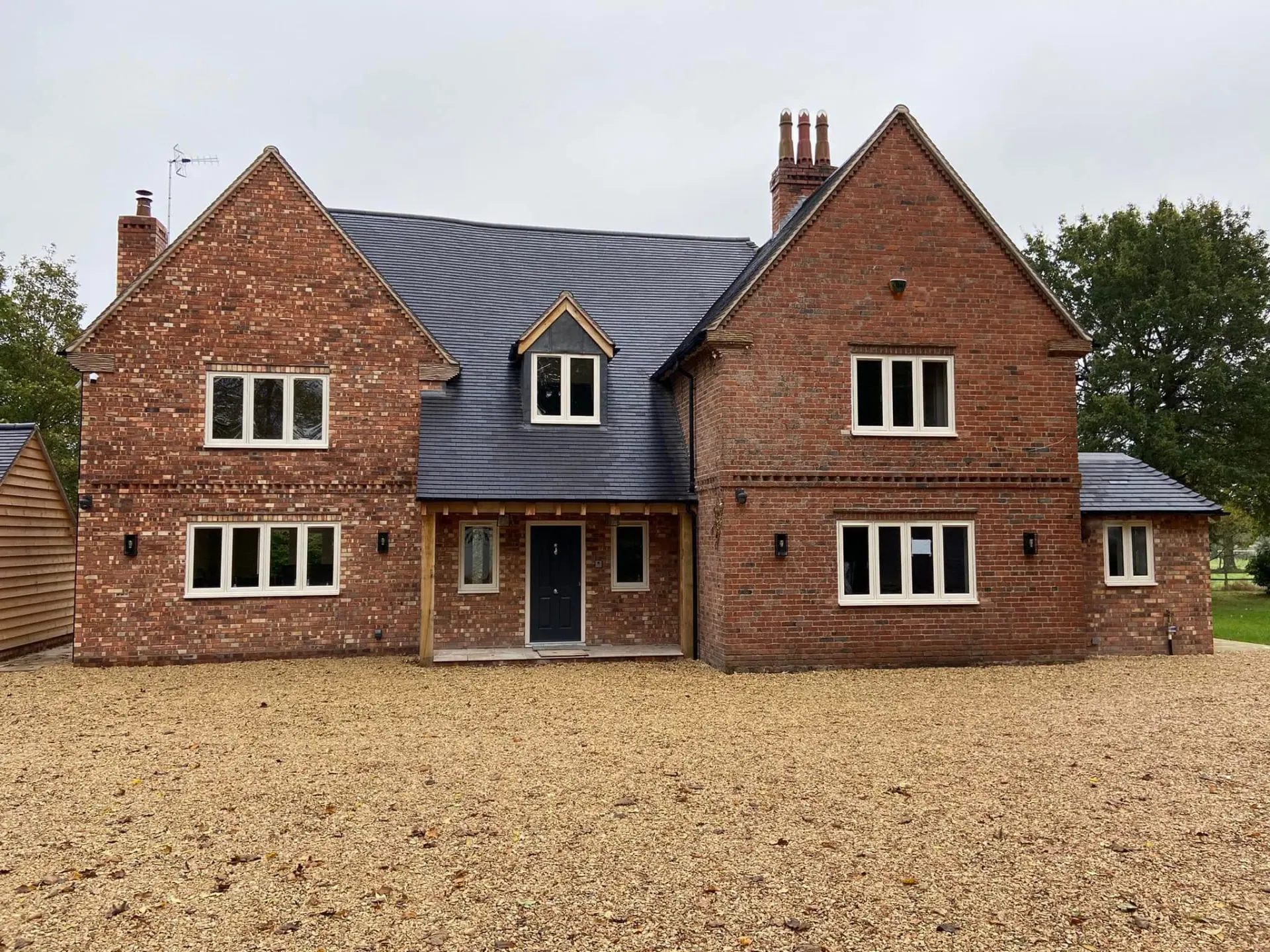 Finished front elevation of the remodelled Wootton Mead house — matching red brickwork, new porch and broad gravel drive, completed by JRC Developers