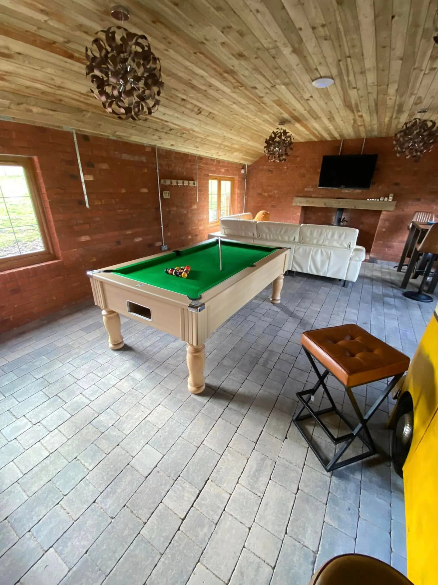 Pool table, leather corner sofa and wood burning stove in the brick niche inside the finished man cave
