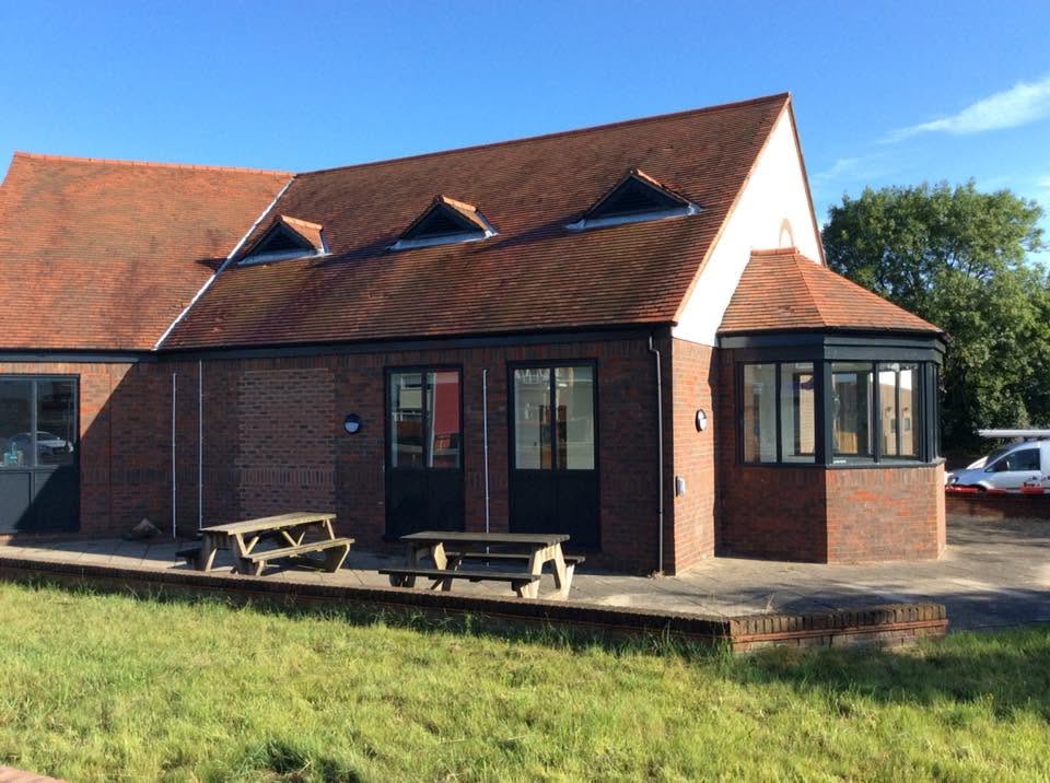 Exterior of the veterinary practice showing brick elevations, dormer windows, a bay window pod and a paved terrace with picnic bench seating