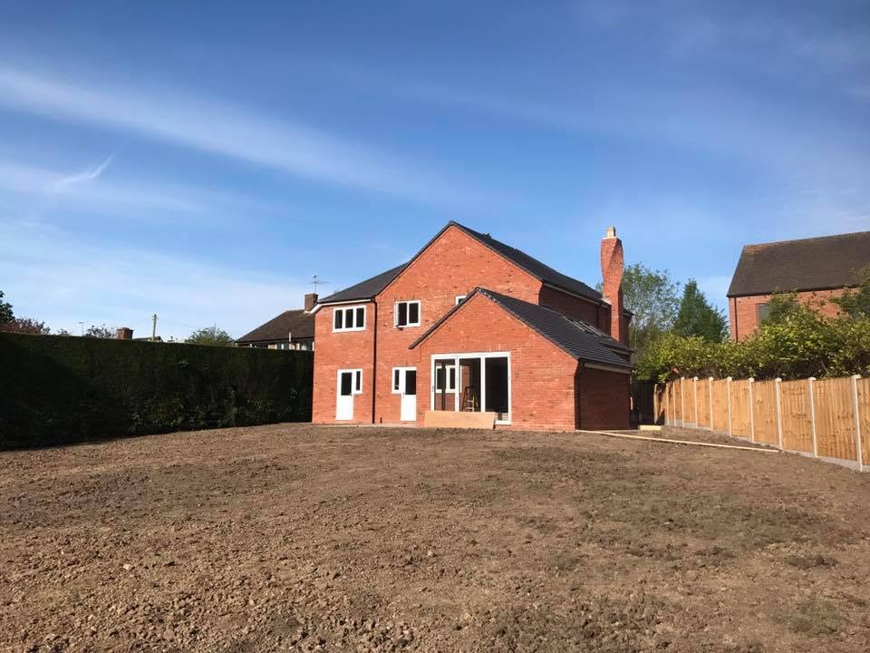 Rear elevation of the Inkberrow new-build before garden landscaping, showing bare soil plot and finished brickwork