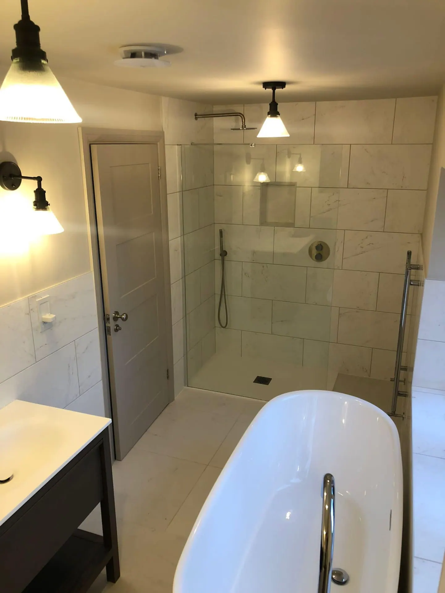 Large bathroom with freestanding bath and walk-in shower finished in marble-effect wall and floor tiles
