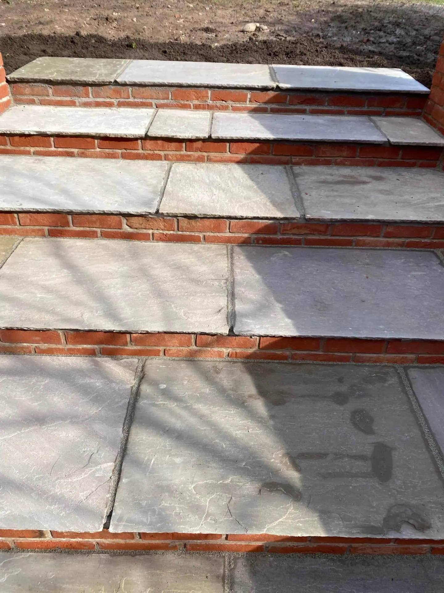 Close-up of riven Indian sandstone treads laid on red brick risers with tight joints on the new garden steps