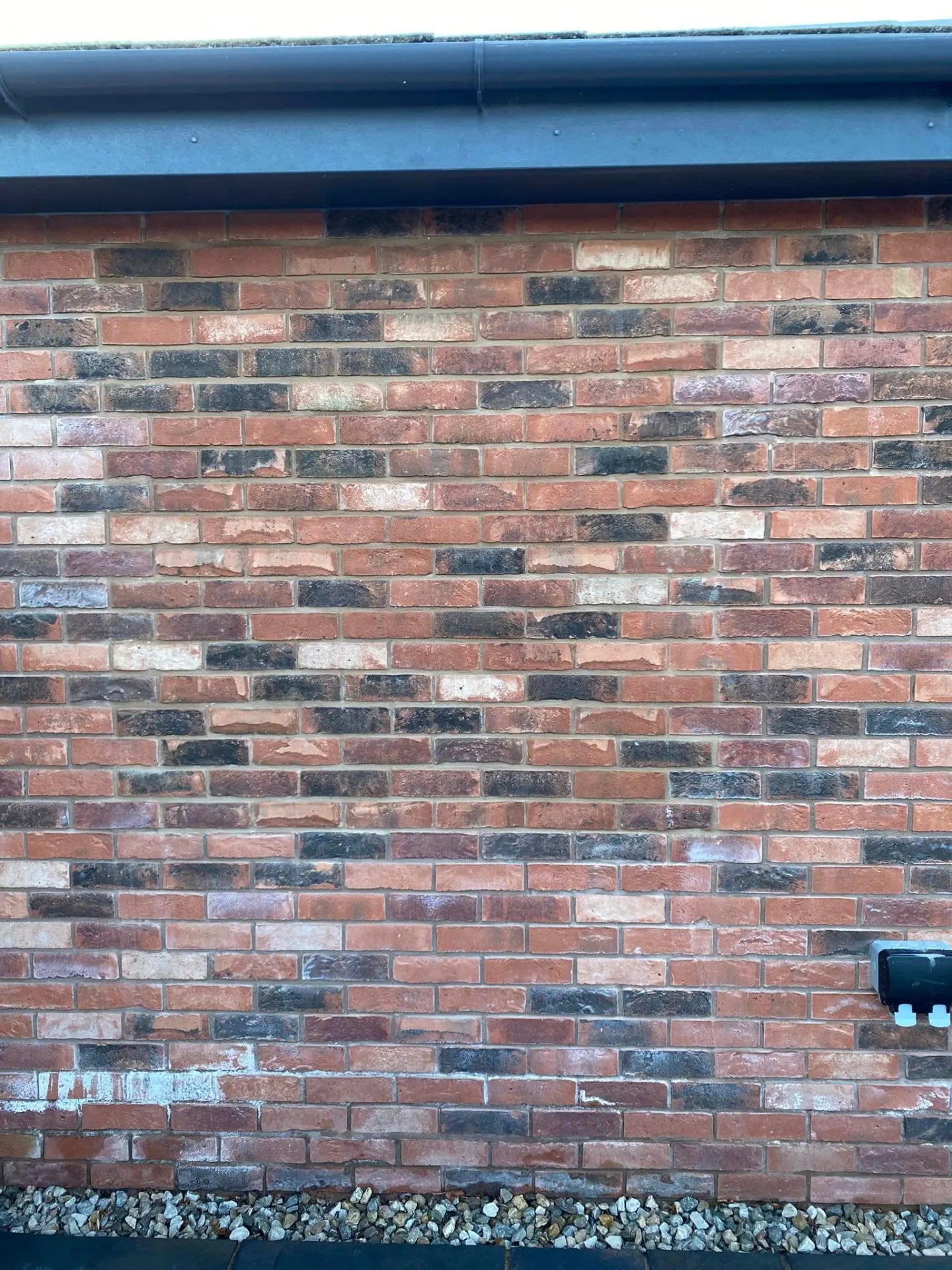 Close view of matched reclaimed-blend brickwork where a new opening was infilled, showing an invisible repair in the existing bond