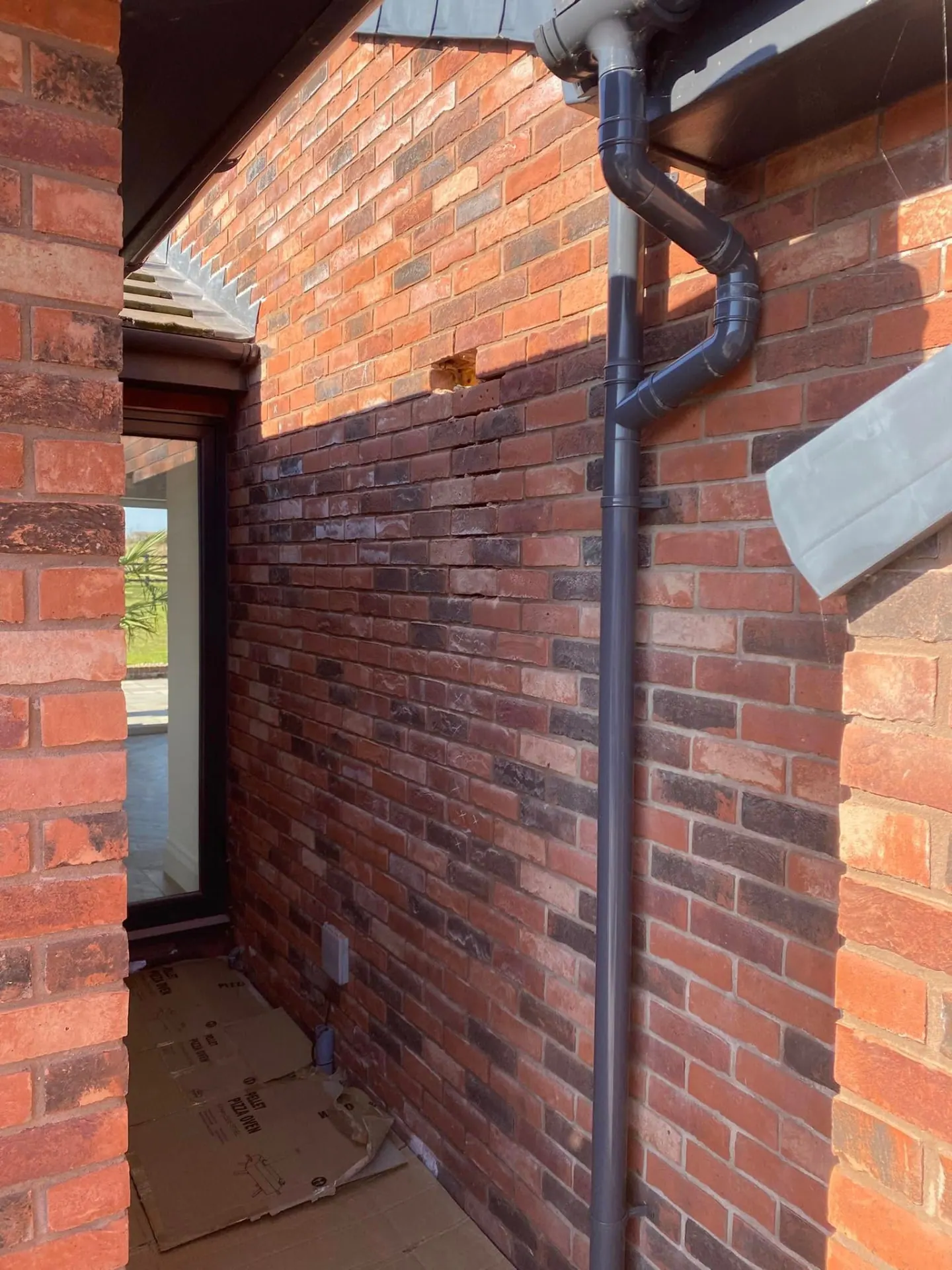 Altered guttering and downpipe against the reclaimed-blend brickwork of the bungalow after the improvement works