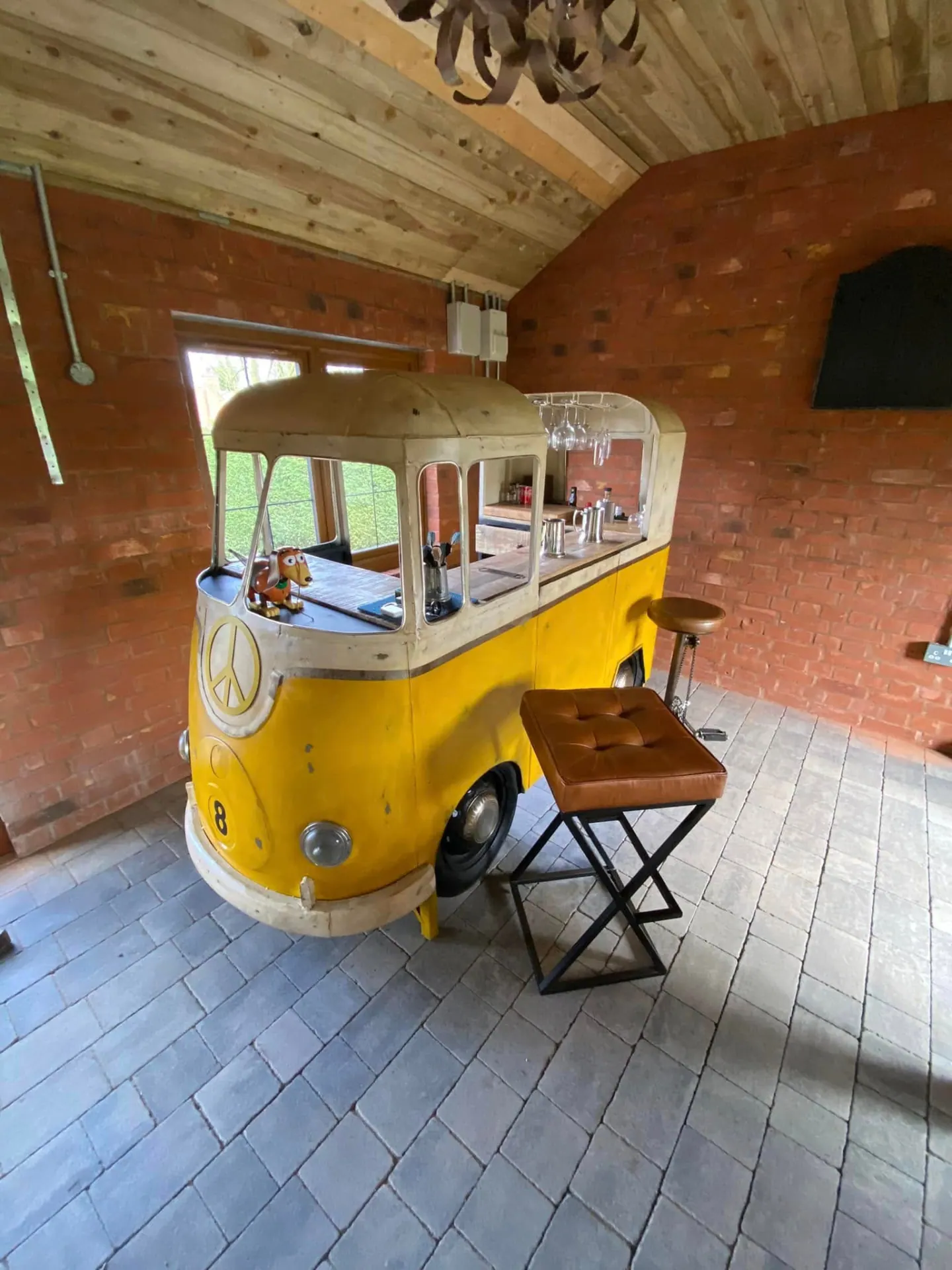 Yellow VW camper van converted into a bar inside the brick man cave under a vaulted timber ceiling
