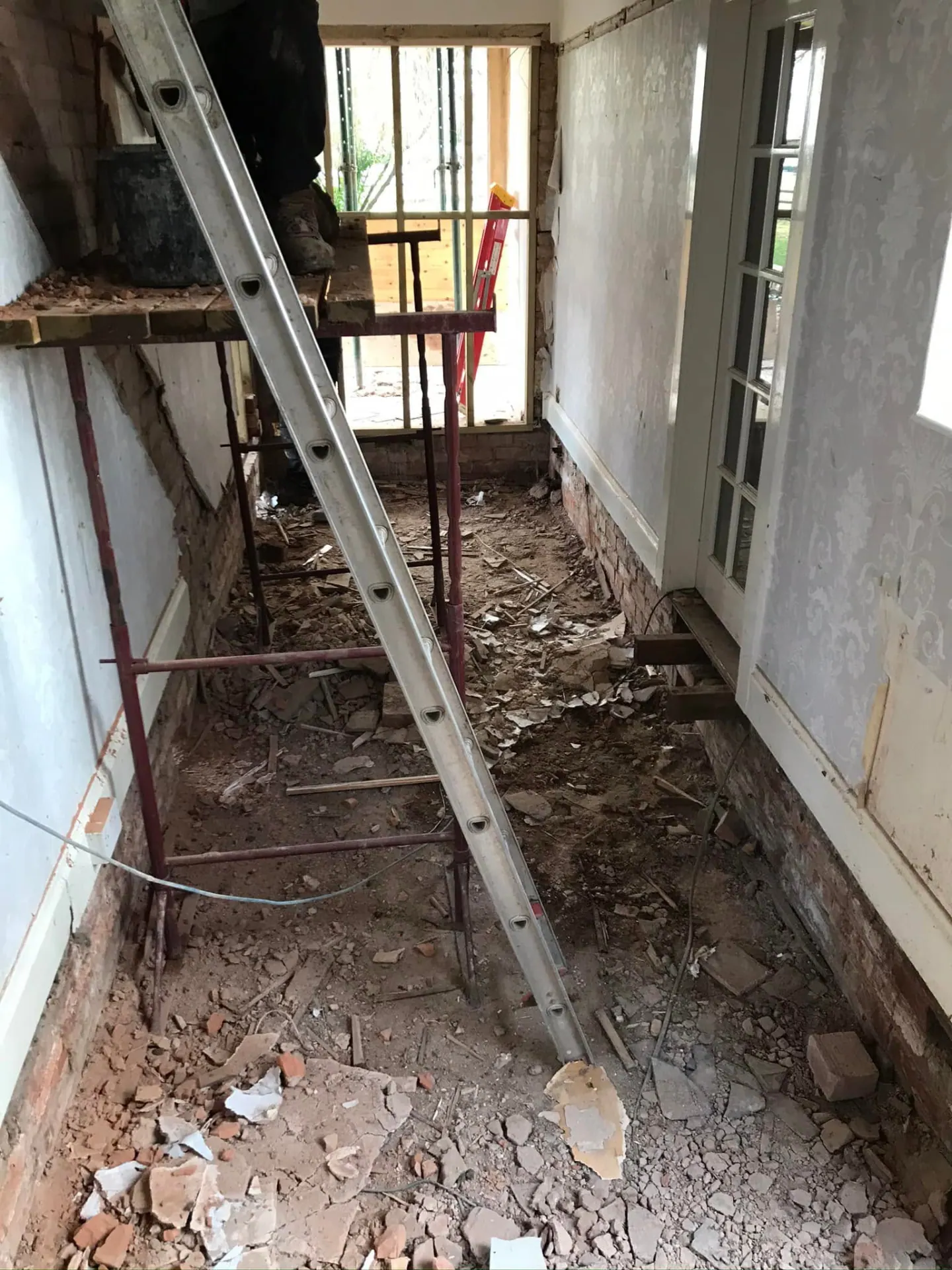 Long internal room stripped out to masonry and floor level during the remodelling process with scaffold and temporary support in place