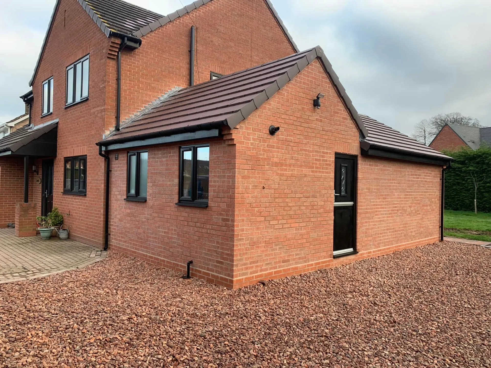 Gable end of the completed side extension with a black composite door and new decorative gravel hardstanding