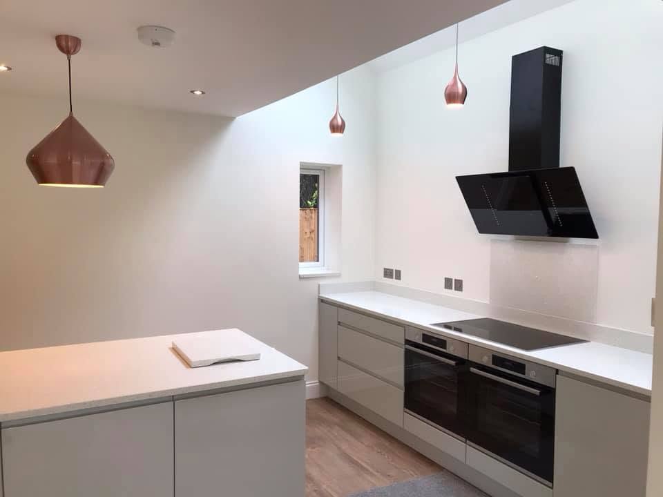 Kitchen island under copper pendant lights and a large skylight at the Inkberrow new-build
