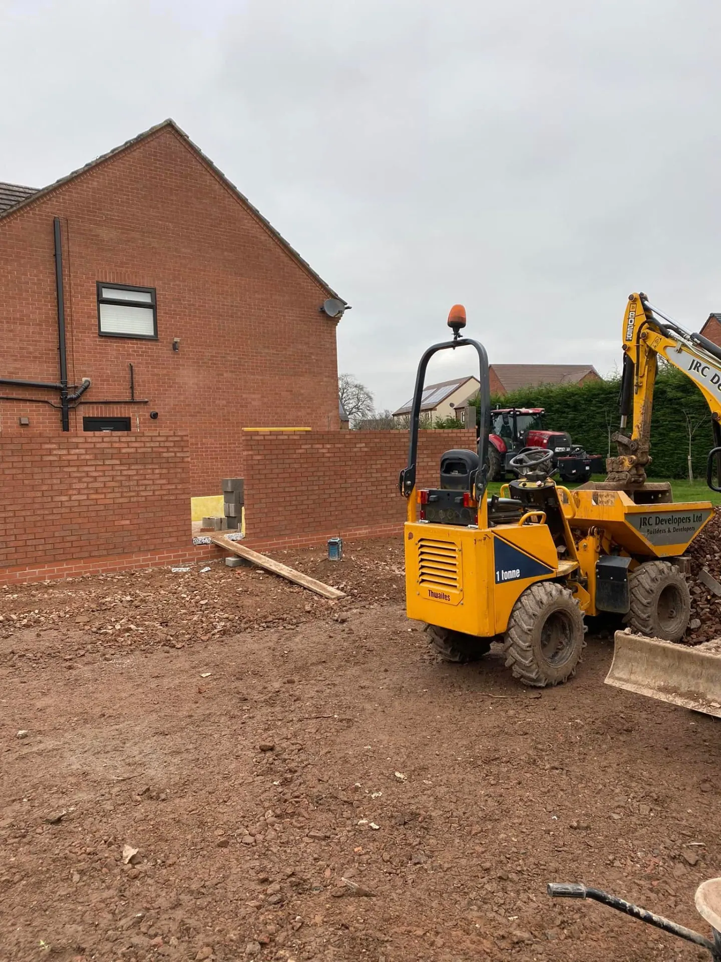 JRC Developers one-tonne dumper and JCB excavator working alongside the new brick wall on the side extension site