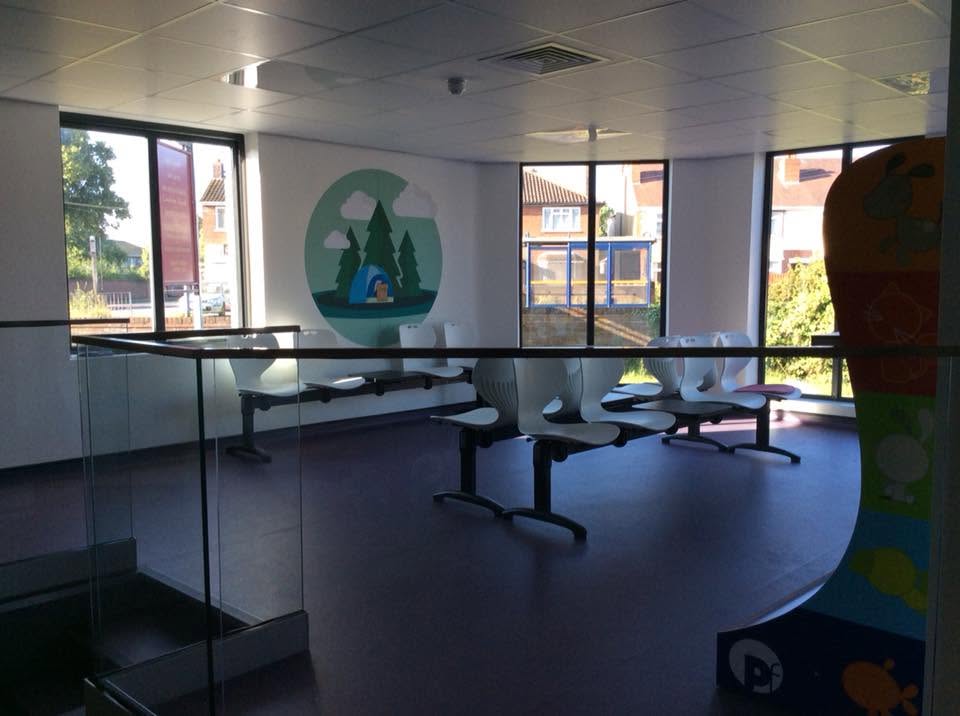 Wide view of the finished veterinary waiting area with glass balustrade, seating banks, illustrated wall graphics and bay windows on three sides