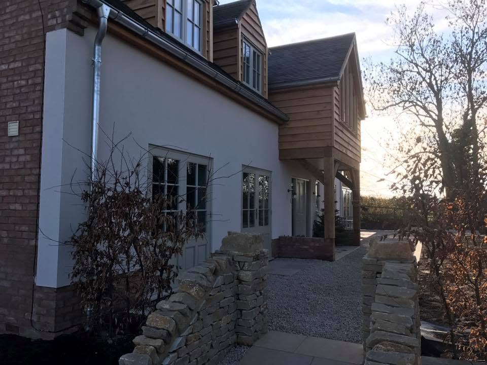 Front elevation of Willow House with oak frame, cantilevered clad first floor, white render and dry stone walling