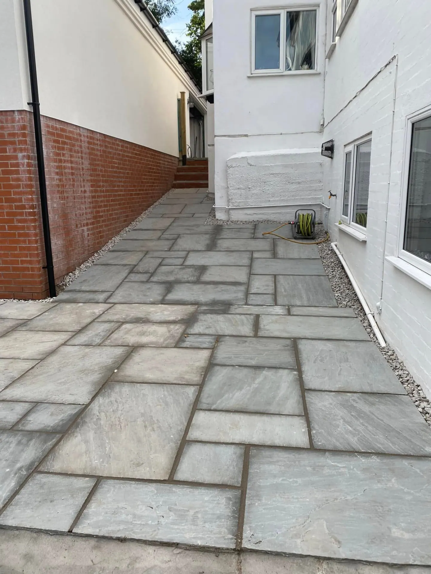 Indian sandstone side path with white gravel margins against the brick plinth of the Whiteoaks annexe